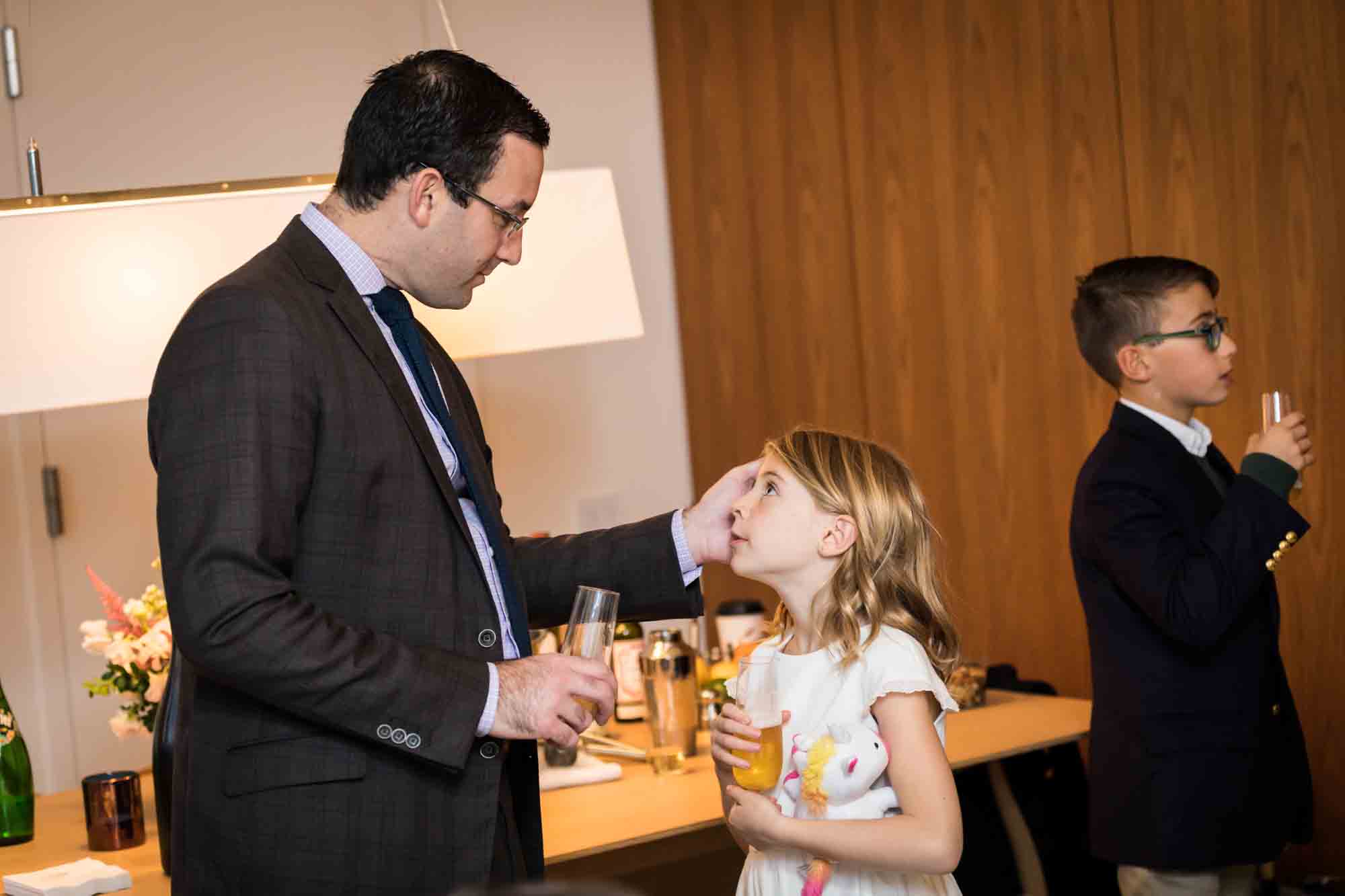 Father touching little girl with glass in hand