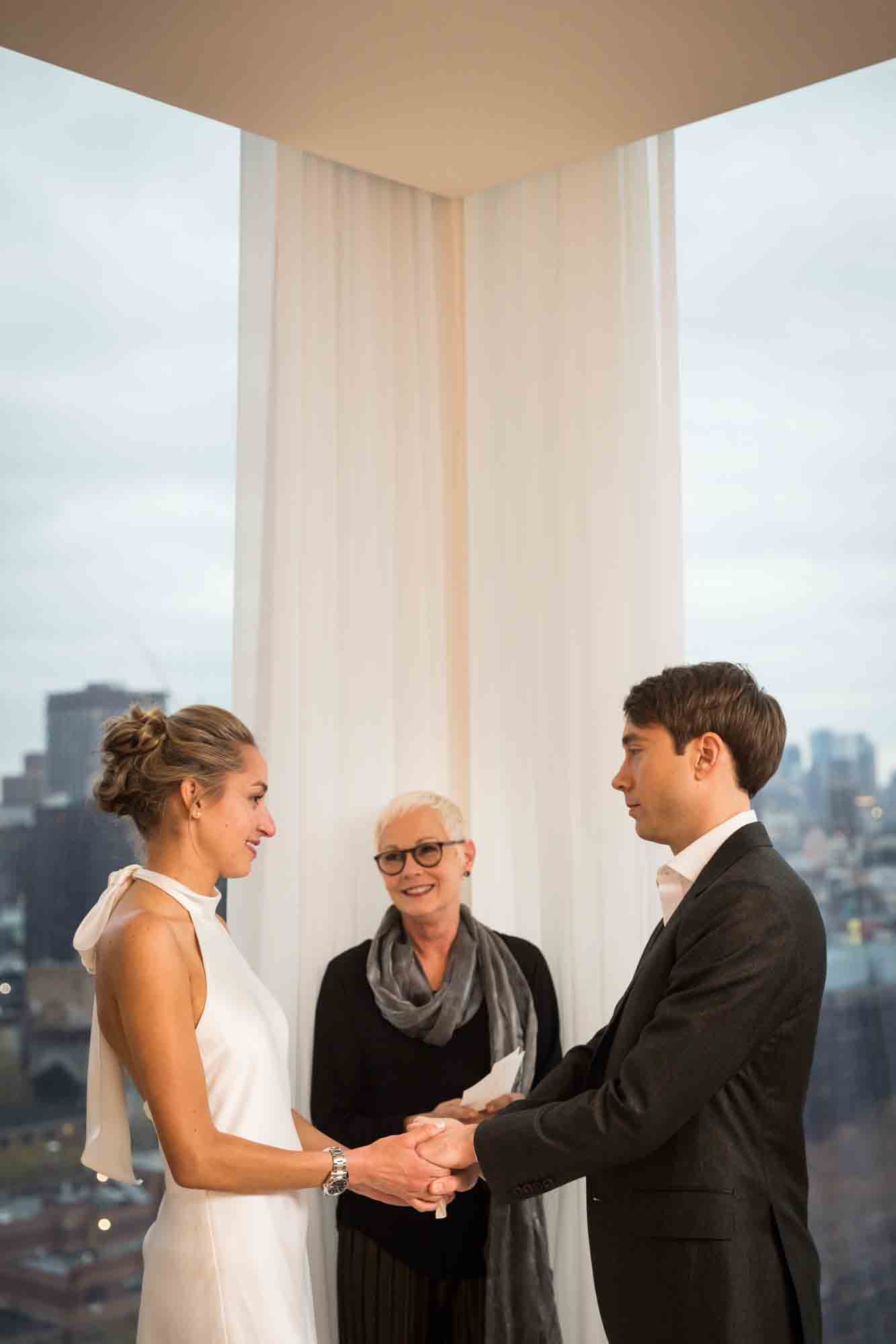Bride and groom saying vows in front of window at a Public Hotel wedding