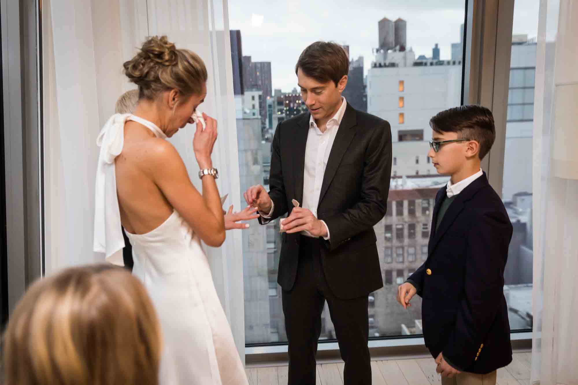 Groom putting ring on bride's finger at a Public Hotel wedding