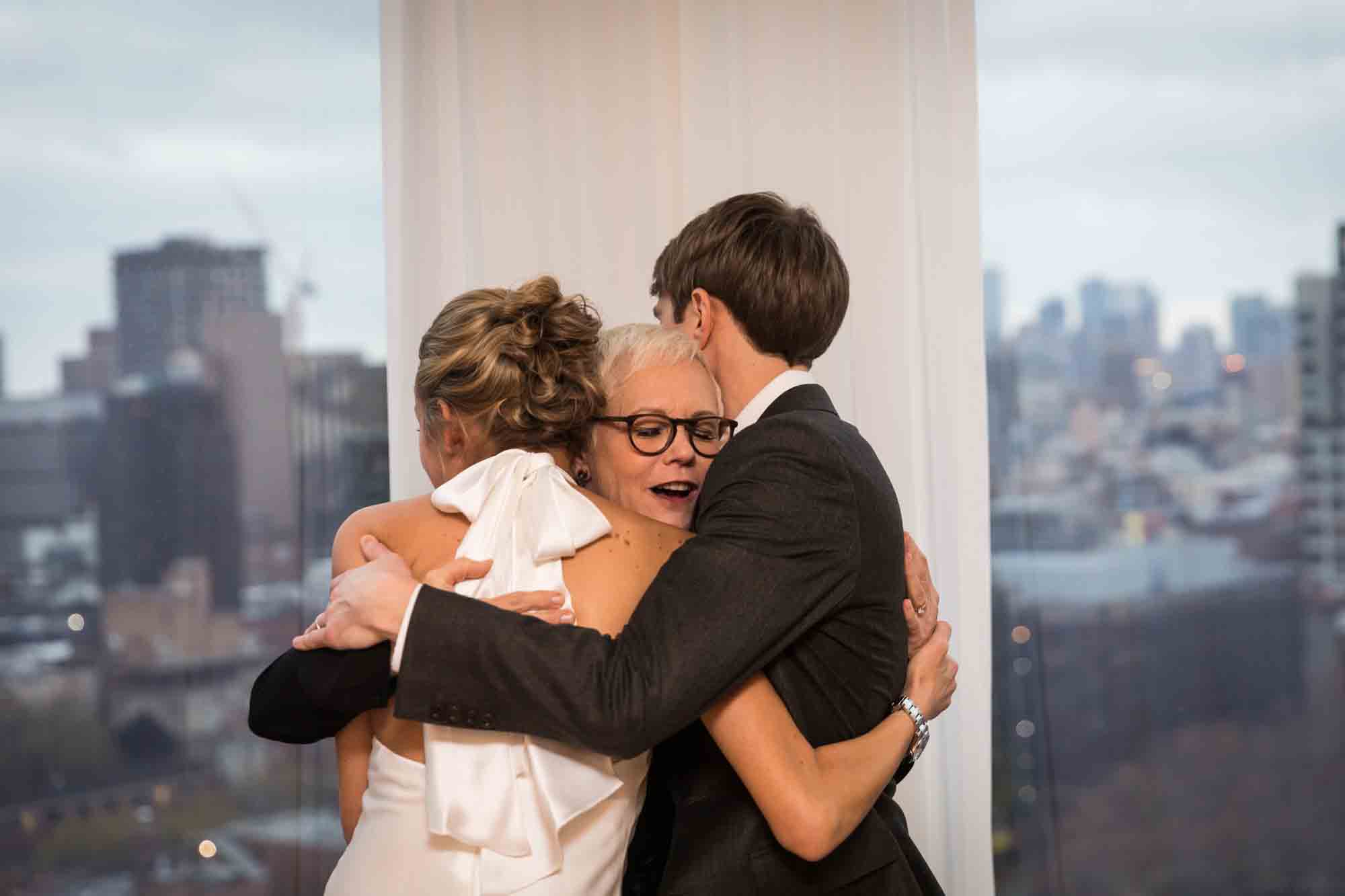 Bride and groom hugging officiant at a Public Hotel wedding