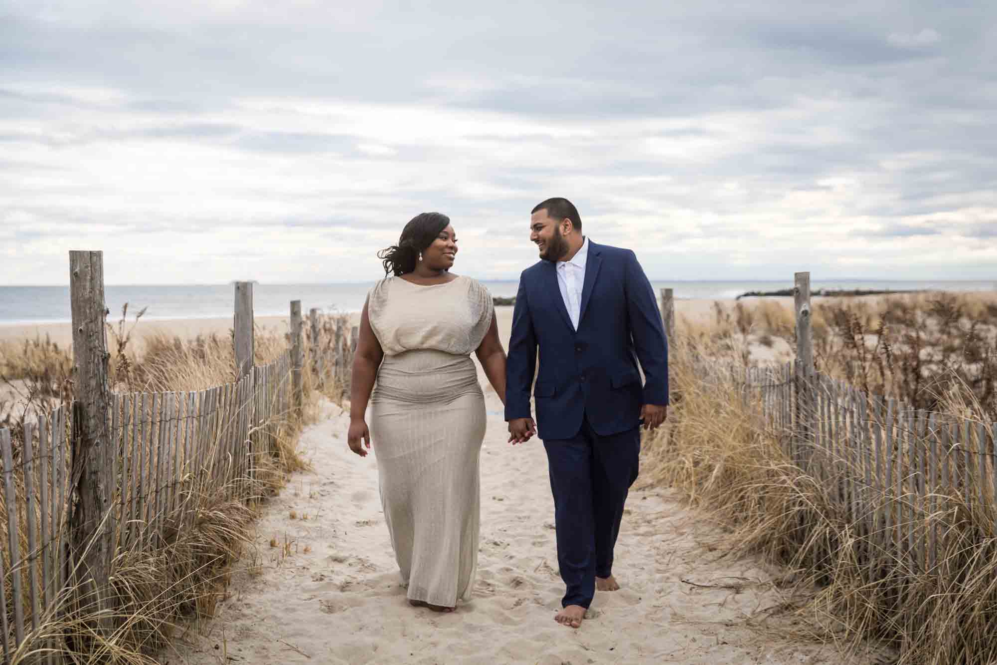 Couple holding hands and walking up beach pathway