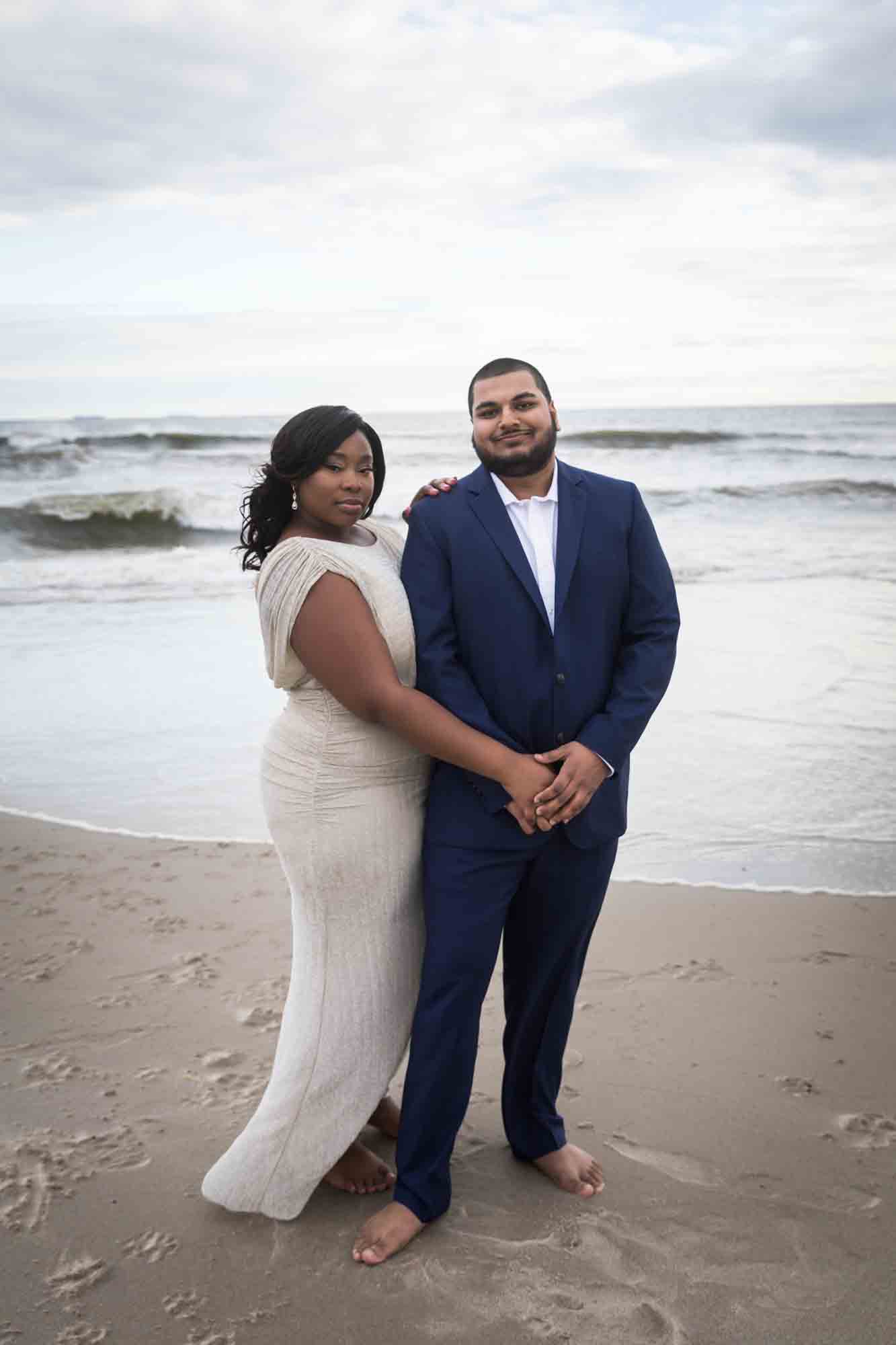 Couple standing in front of waves on beach