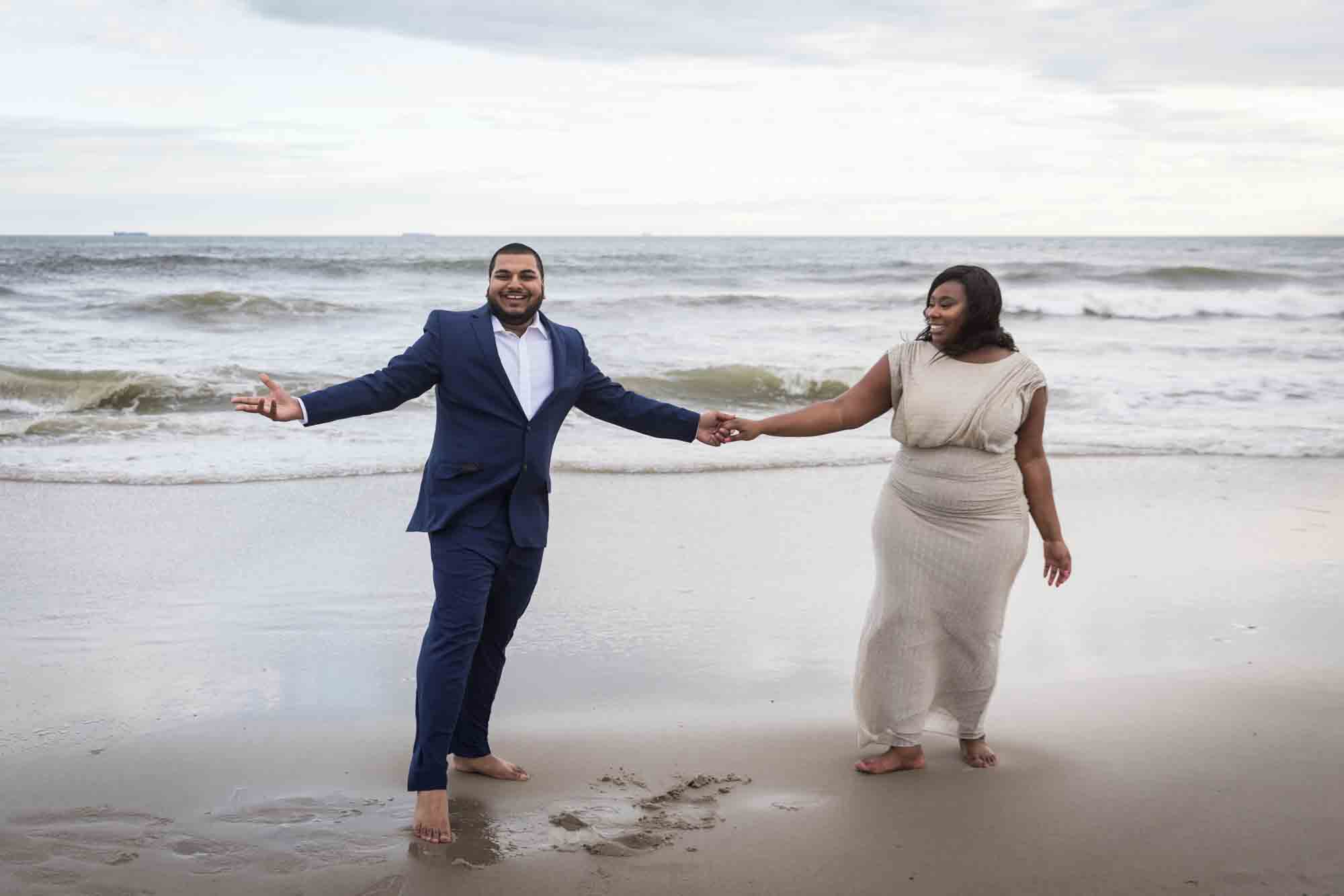 Couple dancing in front of the waves for an article on how to plan the perfect beach engagement photo shoot