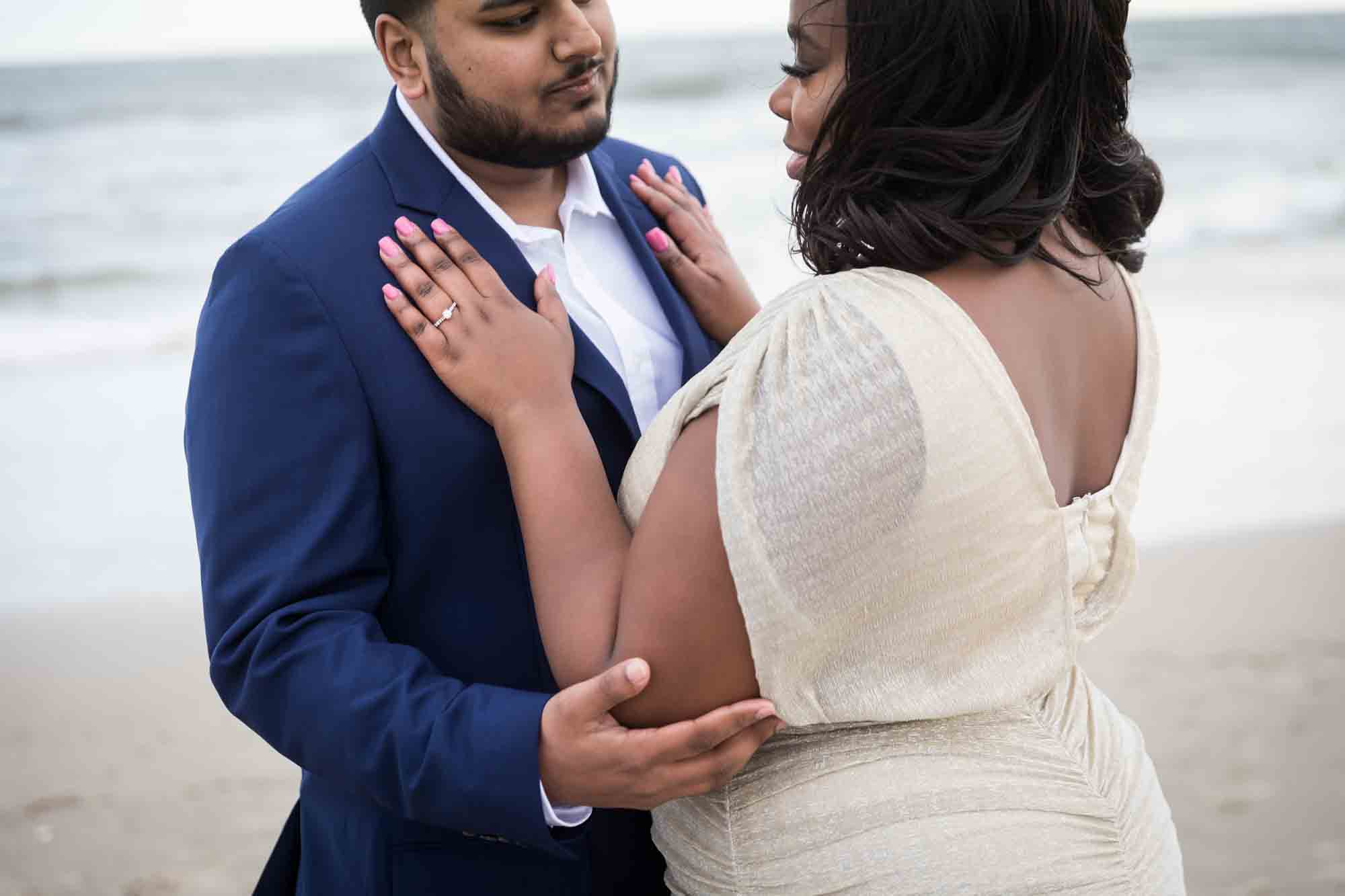 Woman with hands on man's jacket for an article on how to plan the perfect beach engagement photo shoot