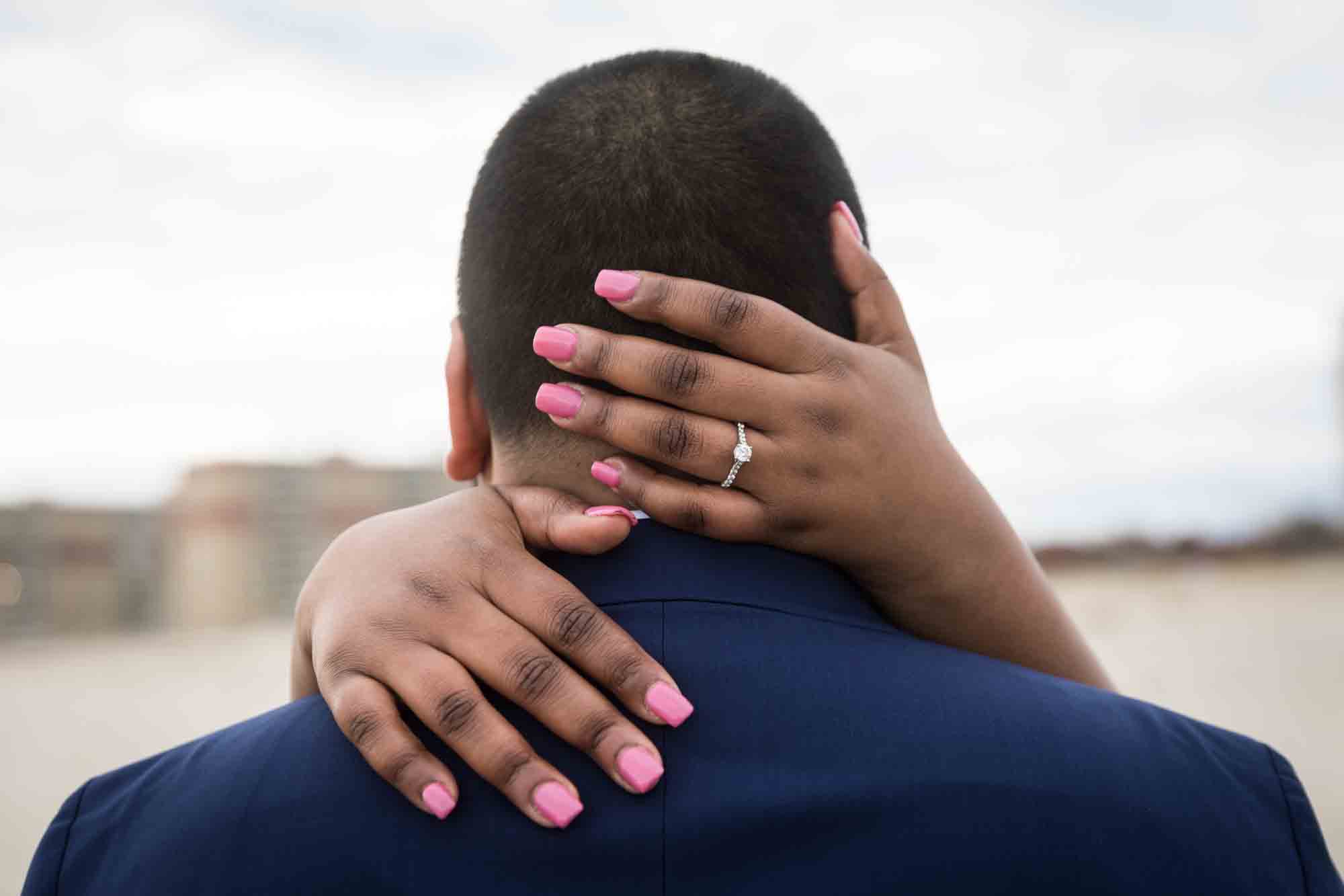 Hands of a woman with pink fingernails wrapped around man's head