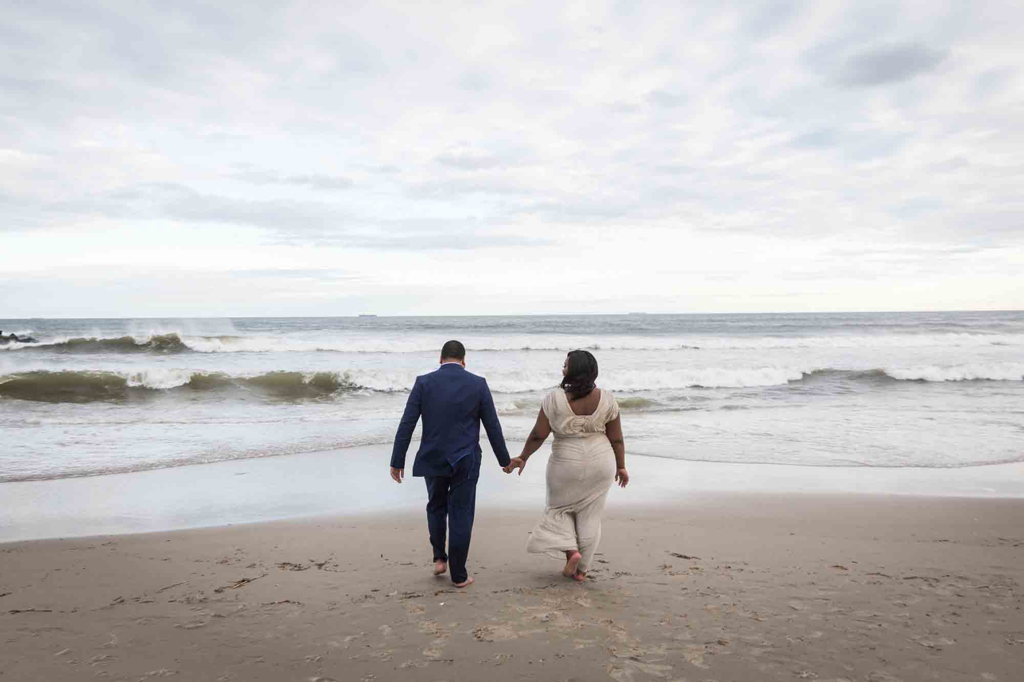 Couple holding hands and walking towards the waves