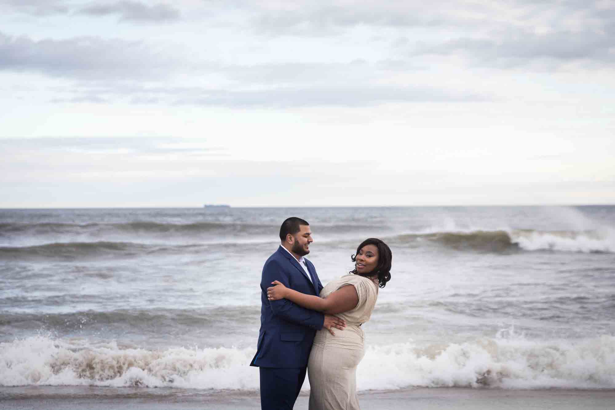 Couple posed in front of waves for an article on how to plan the perfect beach engagement photo shoot