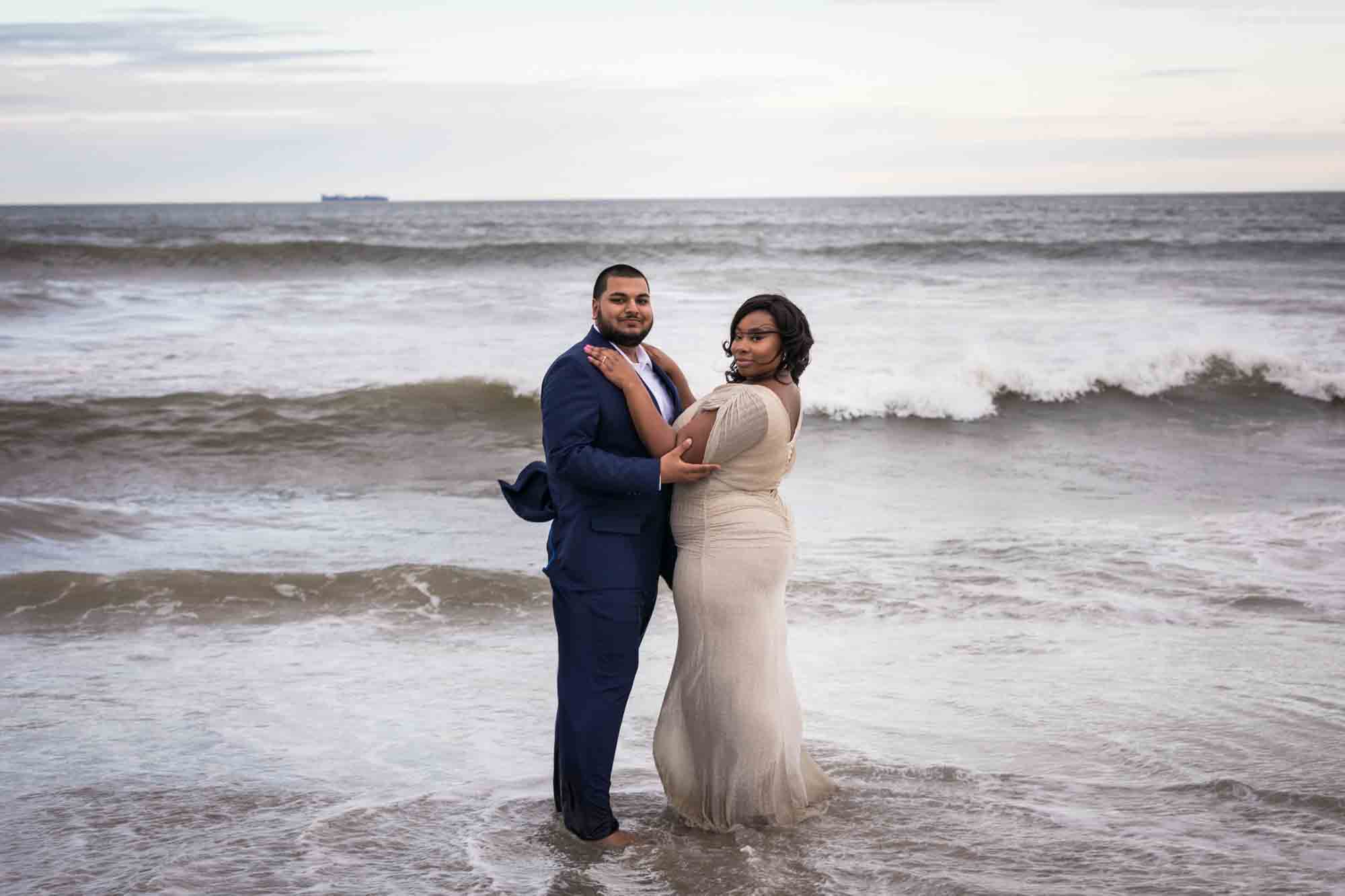 Couple hugging in the water for an article on how to plan the perfect beach engagement photo shoot