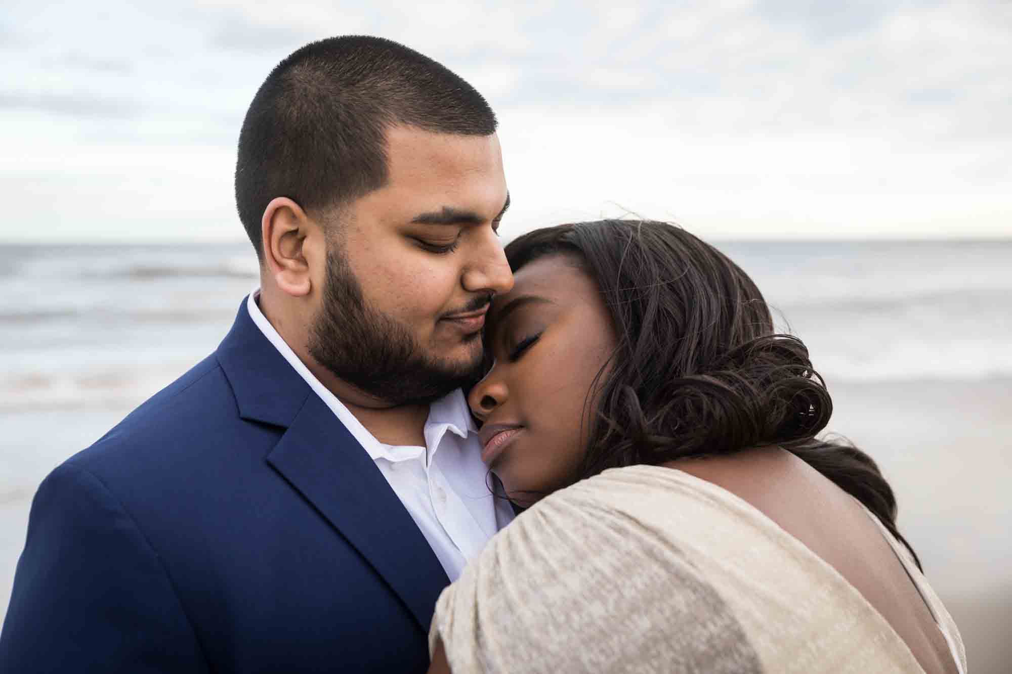 Woman laying her head on man's shoulder for an article on how to plan the perfect beach engagement photo shoot