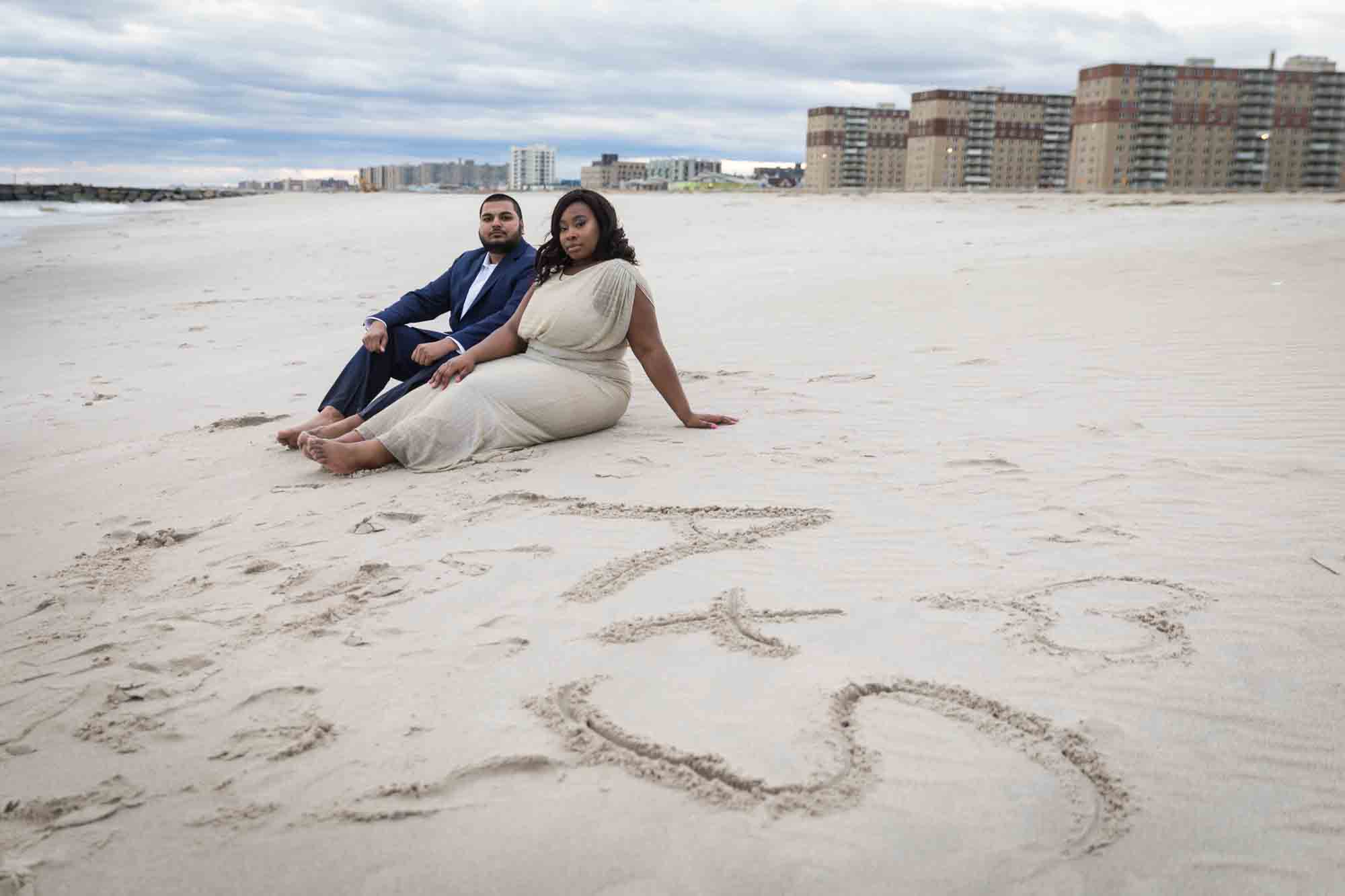 Couple sitting on sand in front of A&S sign
