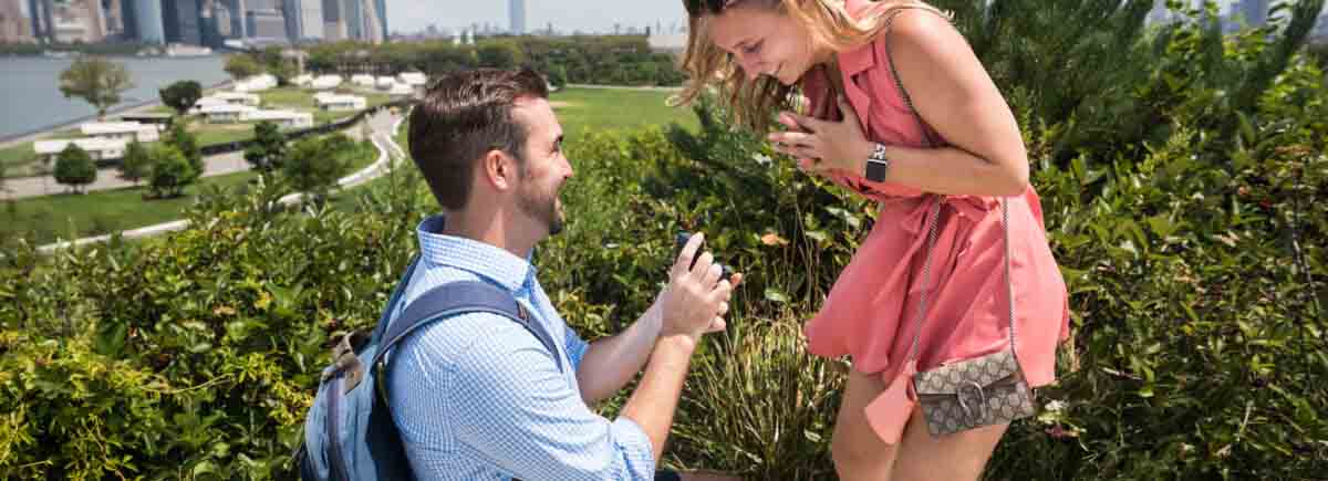 Man on one knee proposing to woman for an article on how to propose on Governors Island