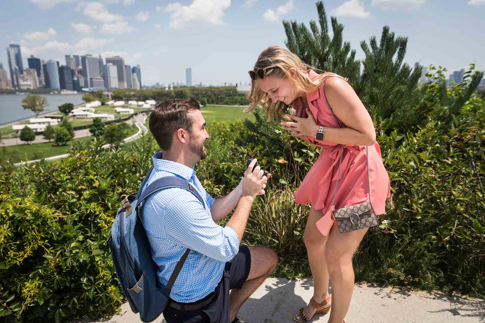 Man on one knee proposing to woman for an article on how to propose on Governors Island