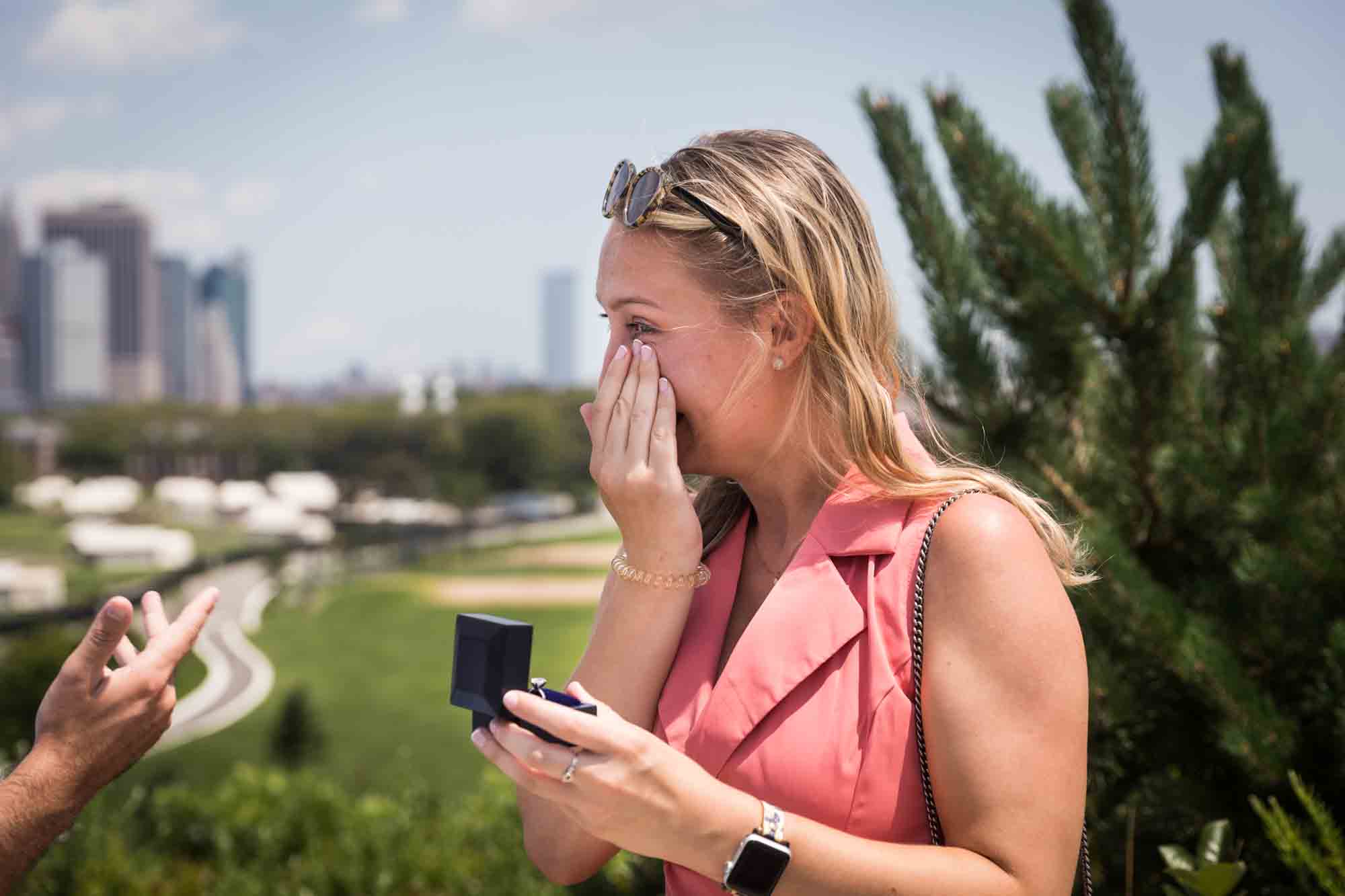 Woman holding ring box and wiping away tear for an article on how to propose on Governors Island