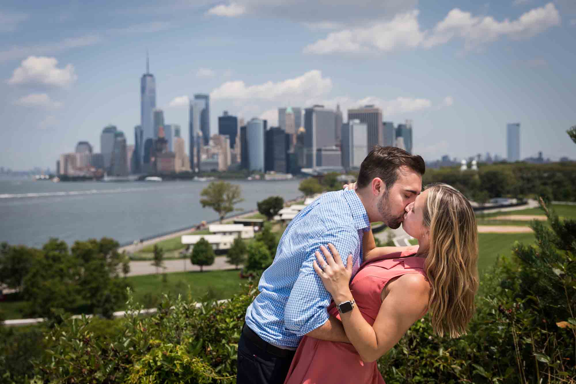 Couple kissing with NYC skyline in the background for an article on how to propose on Governors Island