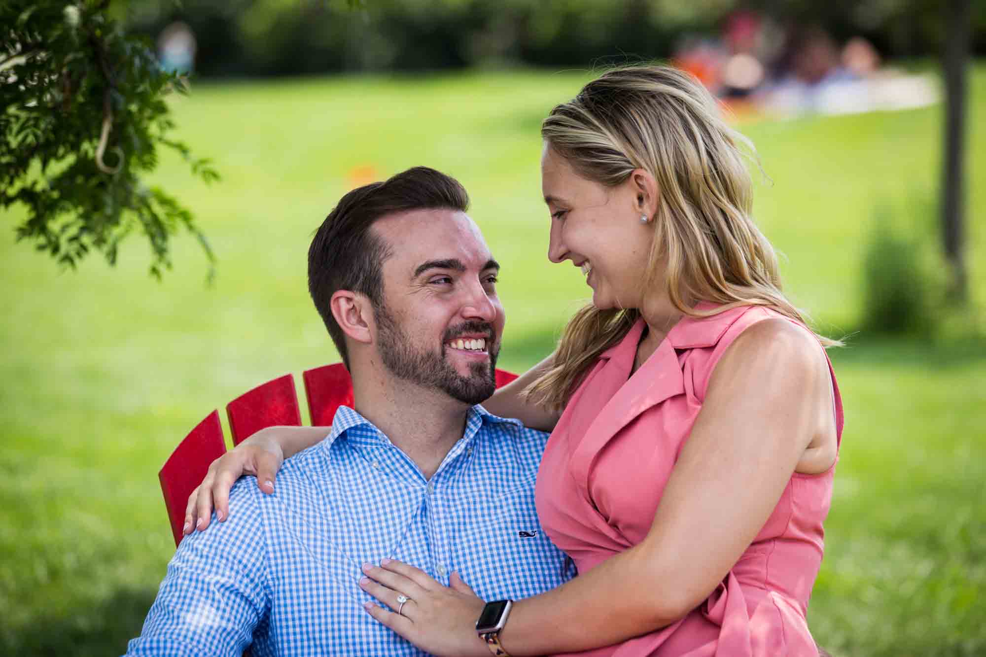 Couple seated on red Adirondack chair for an article on how to propose on Governors Island