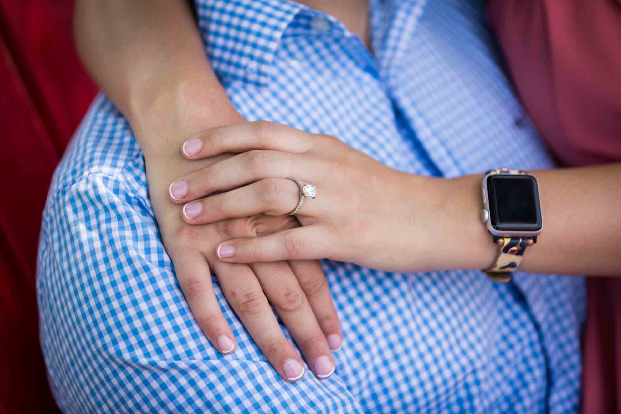 Hands of a woman wearing engagement ring against man wearing blue and white checked shirt