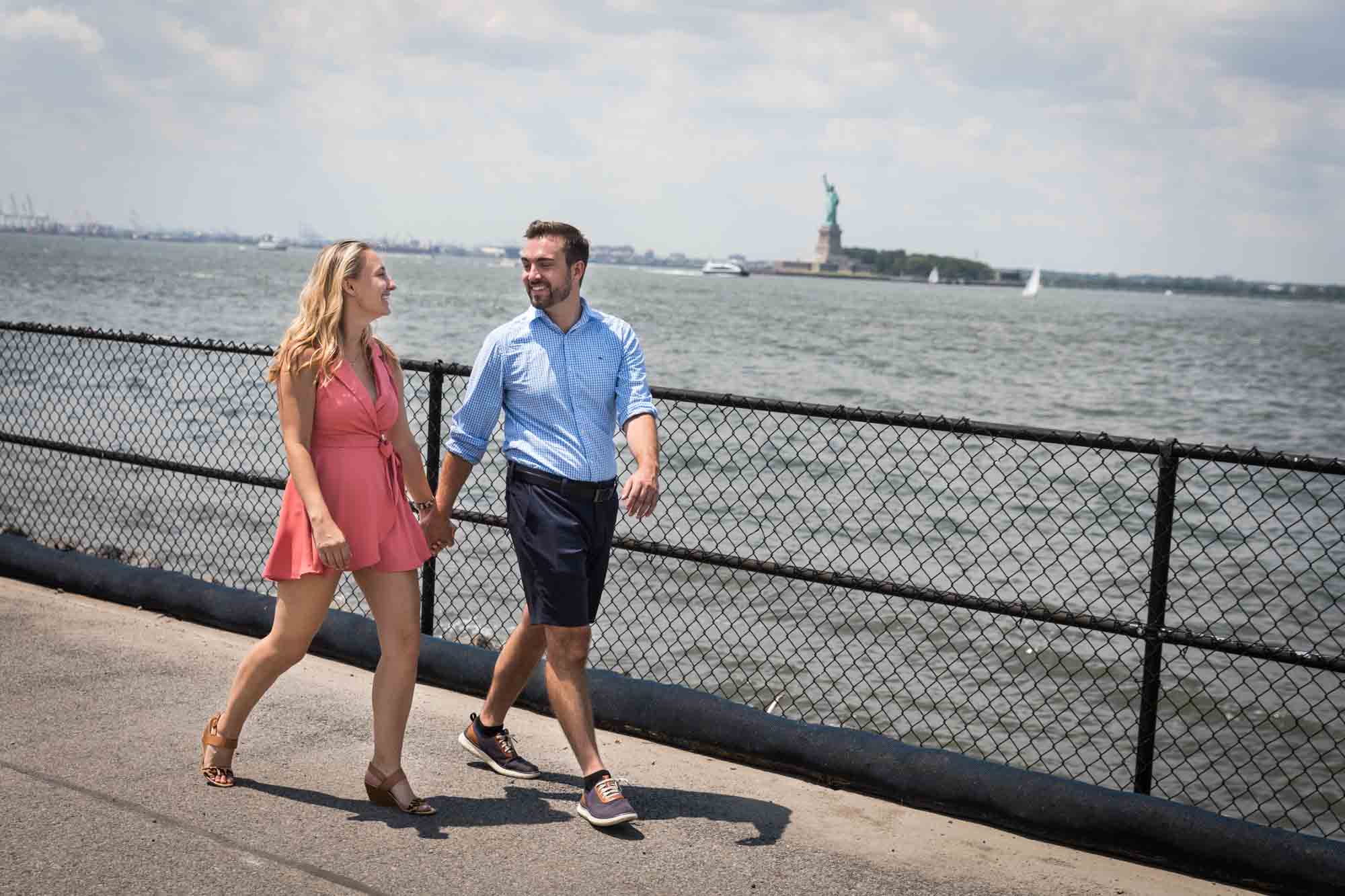 Couple walking on Governors Island with Statue of Liberty in the background