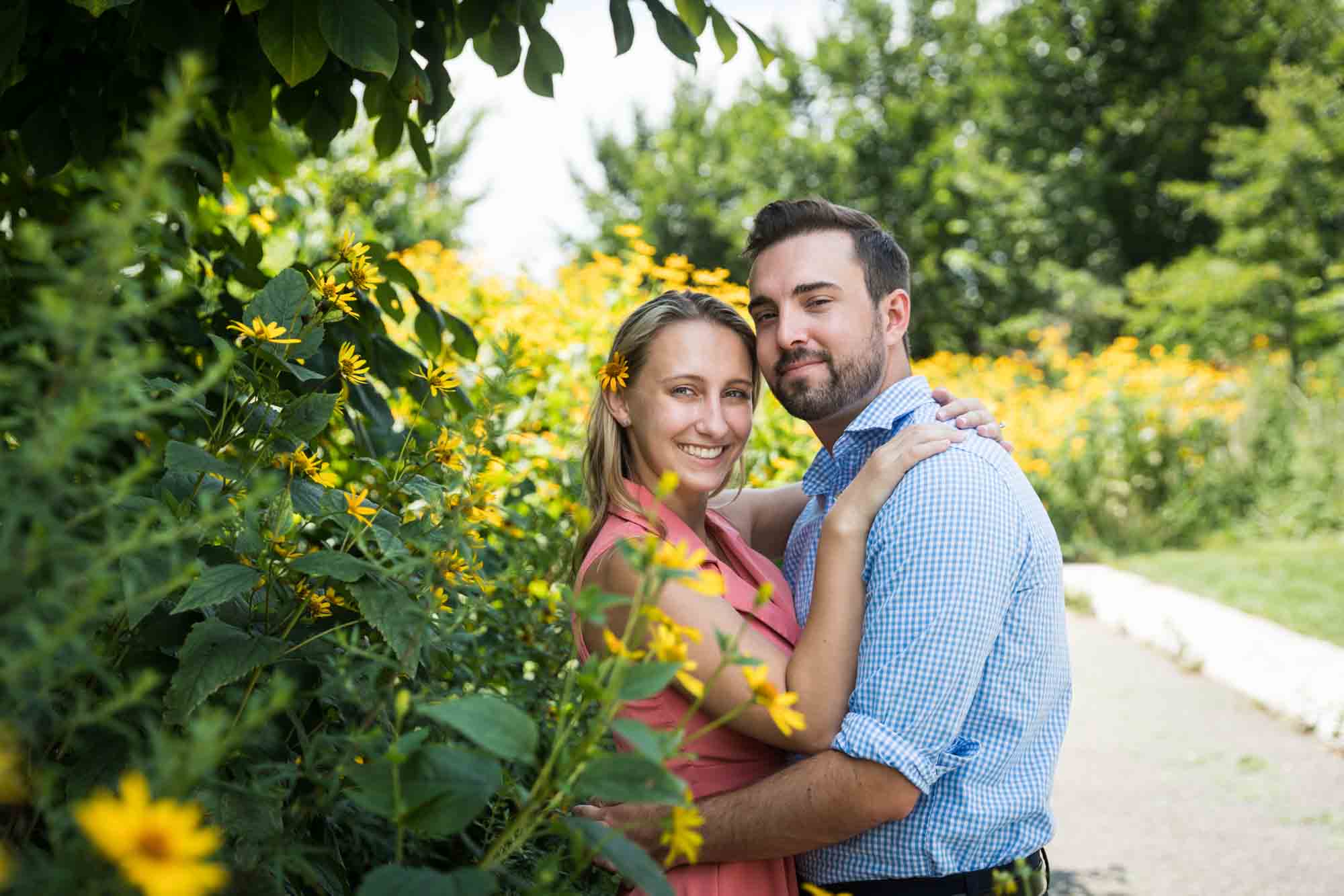 Couple hugging in front of yellow daisies on Governors Island
