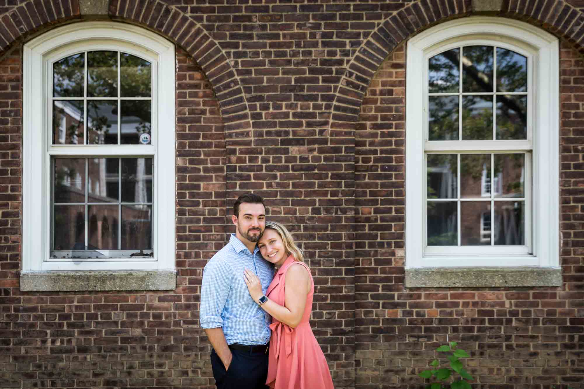 Couple in front of brick facade for an article on how to propose on Governors Island