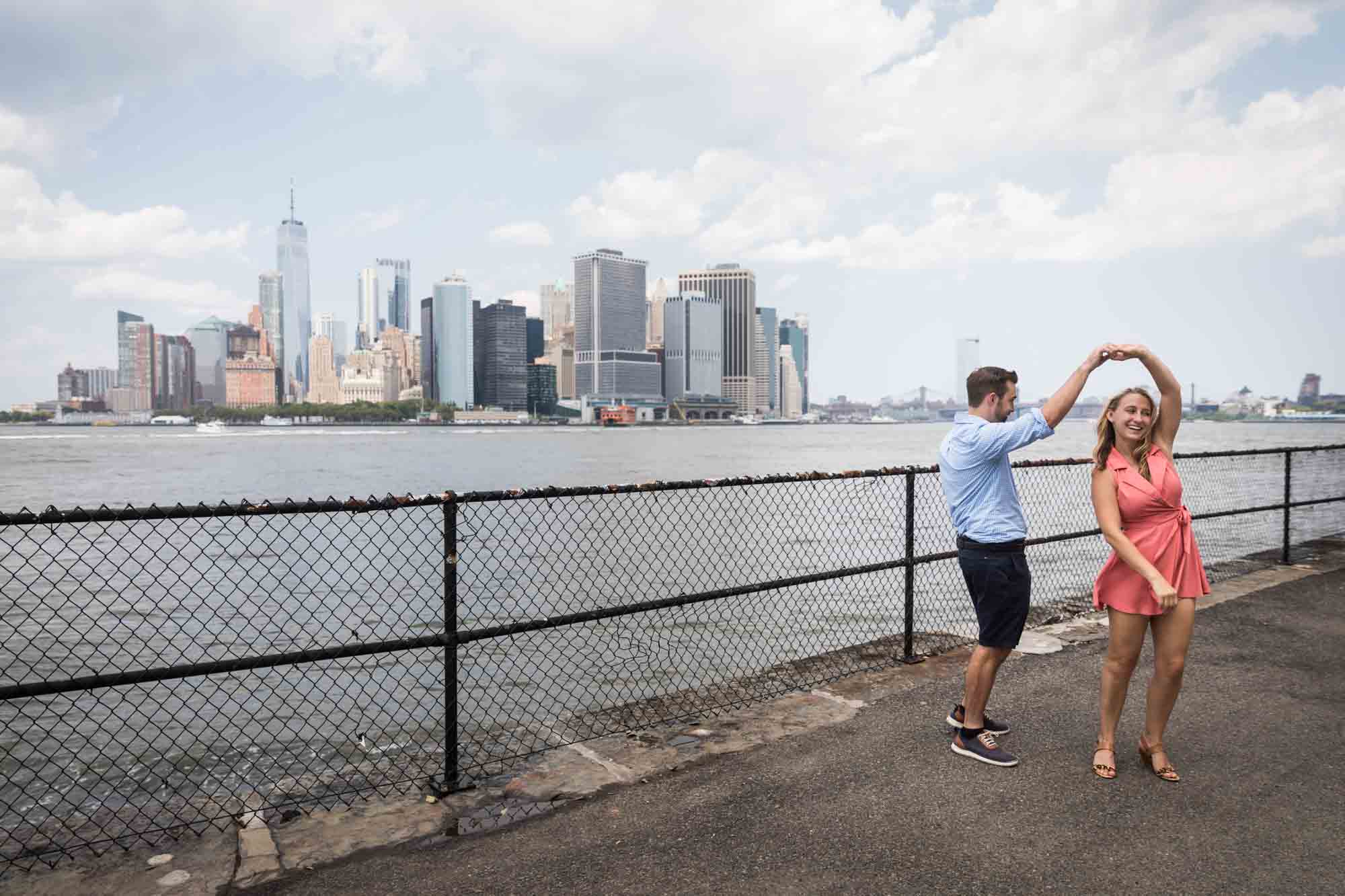 Couple dancing in front of railing with NYC skyline in background