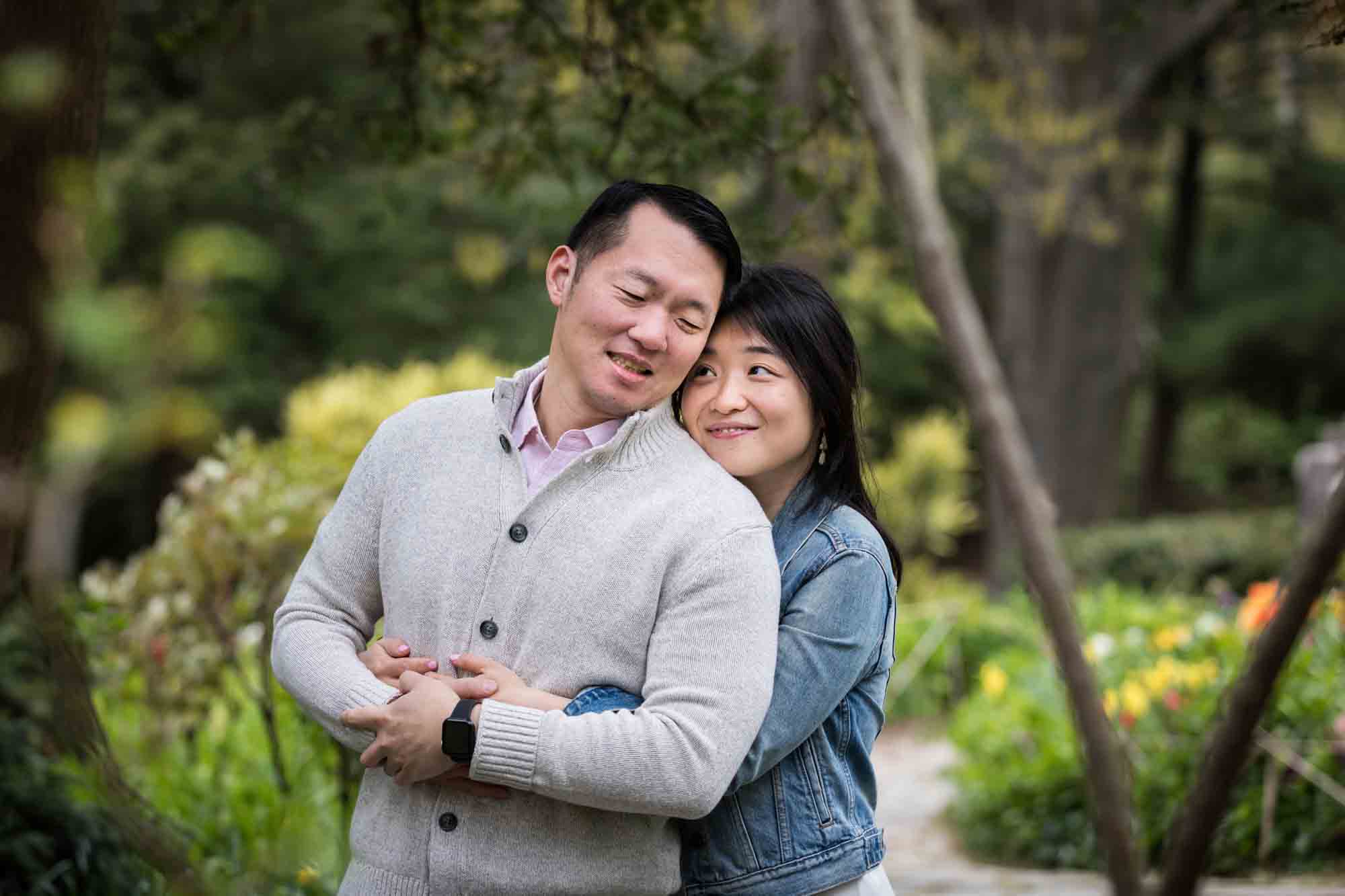 Woman hugging man in Shakespeare Garden during engagement shoot