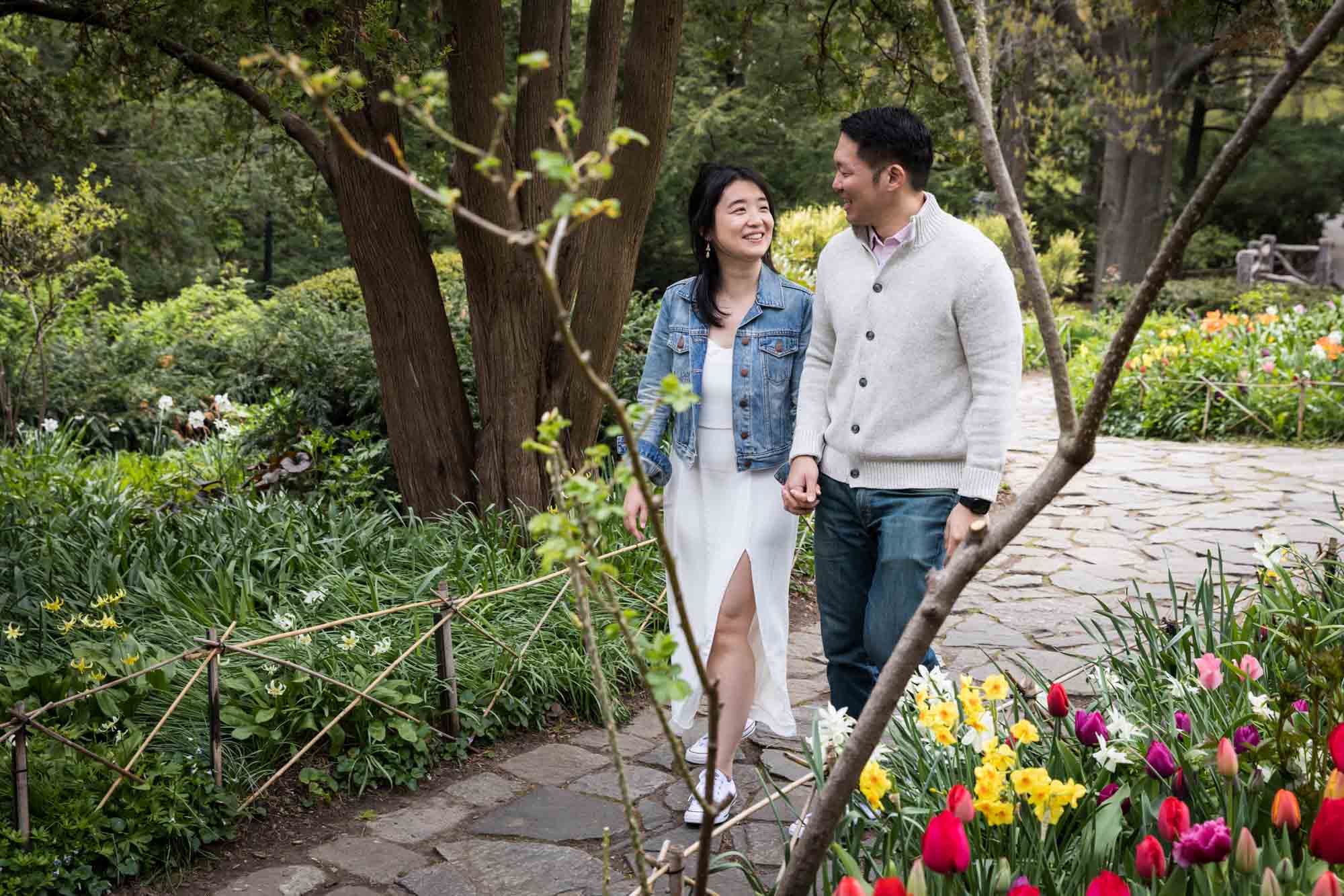 Asian couple walking on pathway in Shakespeare Garden during engagement shoot