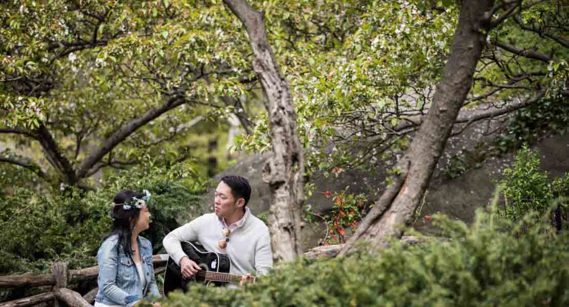 Shakespeare Garden engagement photos of a couple playing guitar in the garden