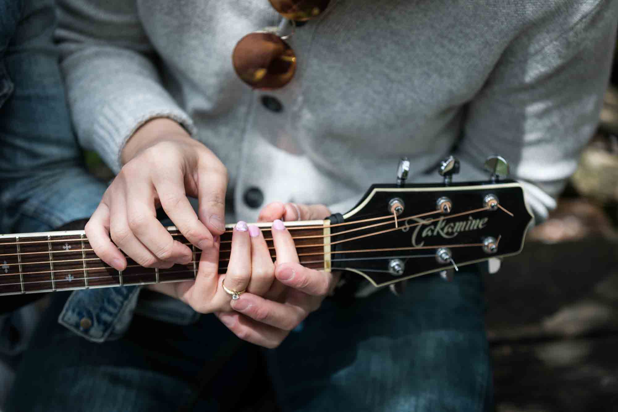 Hands of man placing hands of woman on guitar neck