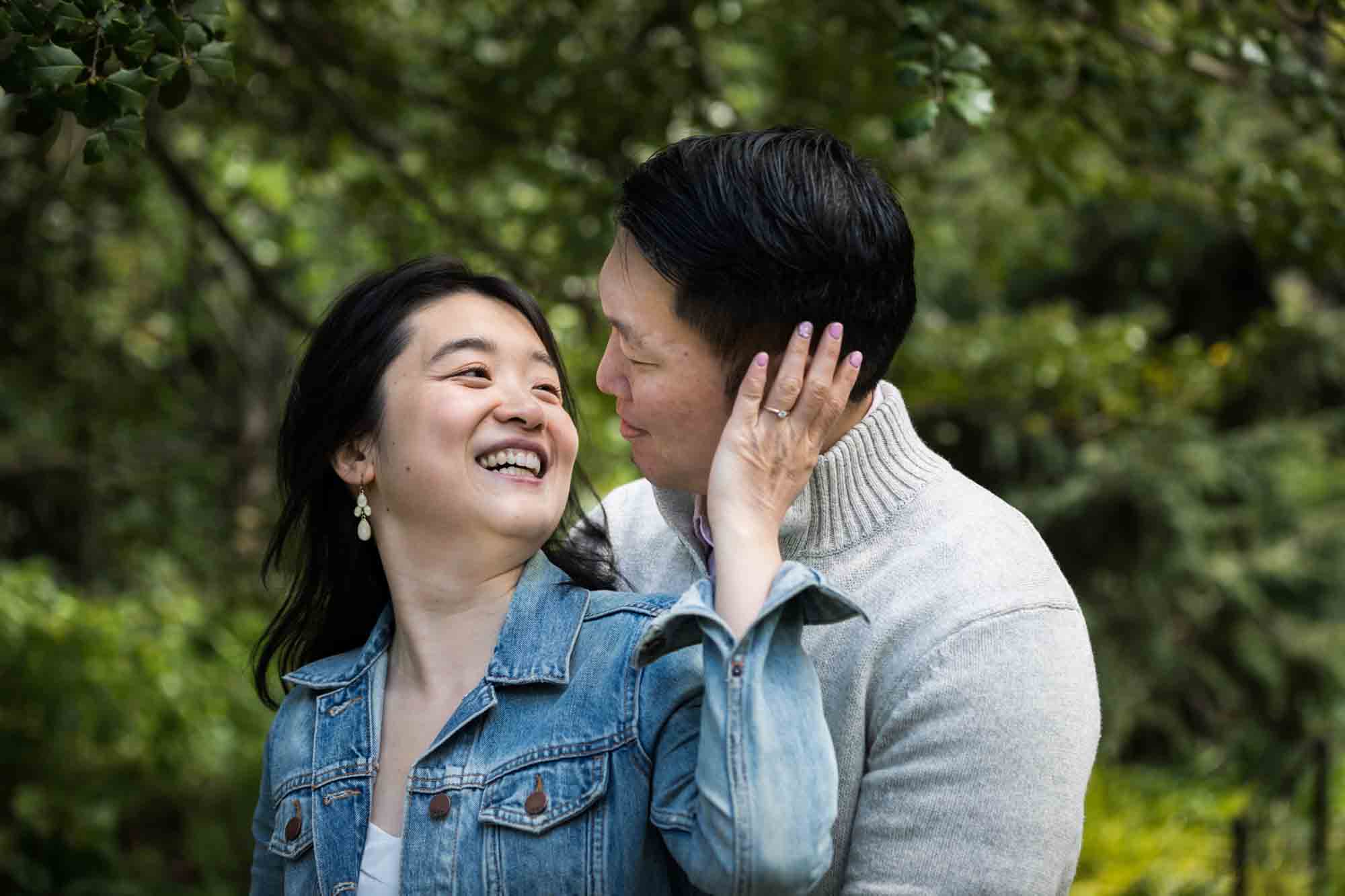Woman putting hand on man's cheek in Shakespeare Garden during engagement shoot