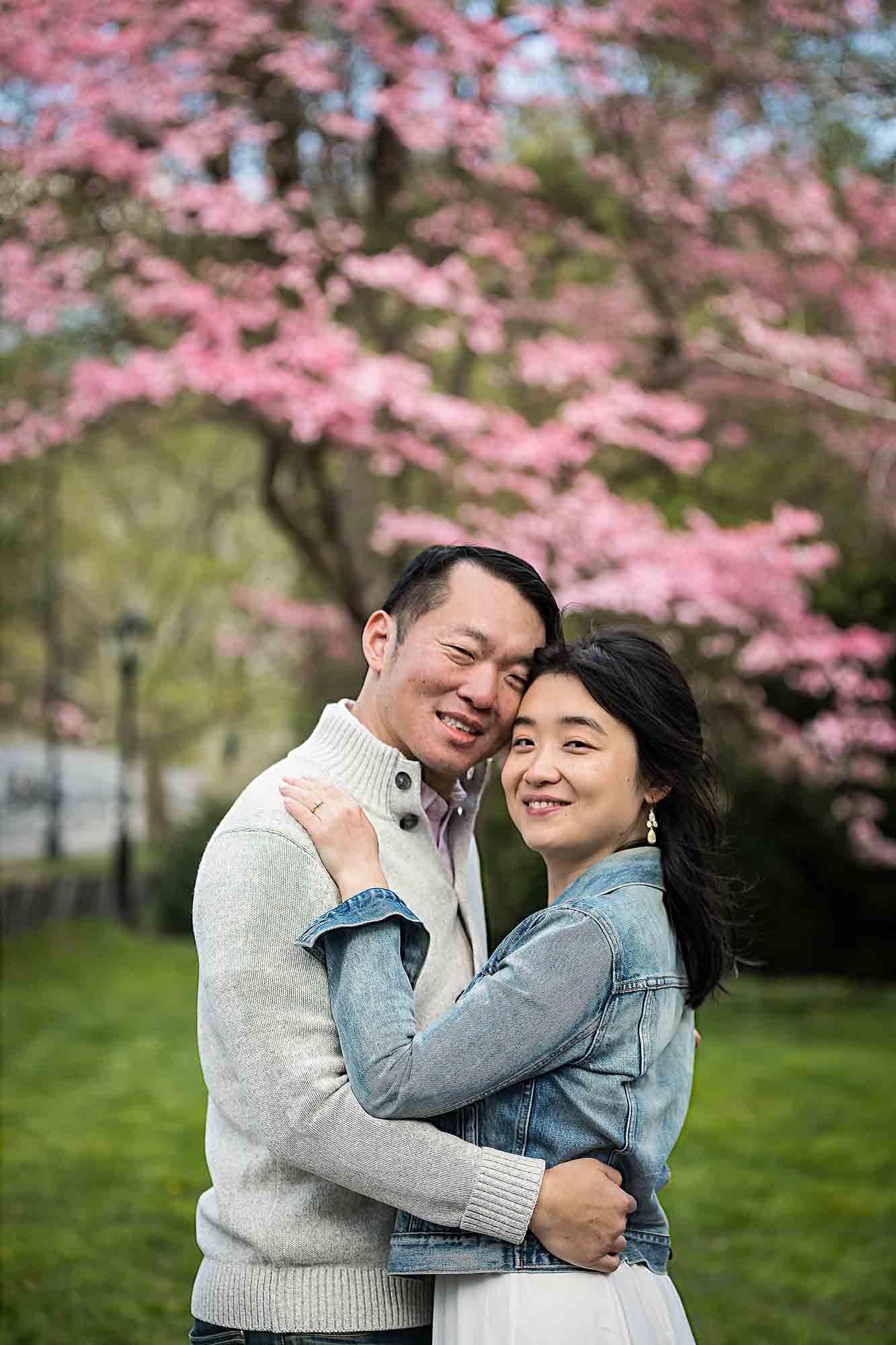 Couple hugging in front of pink flowering tree in Central Park