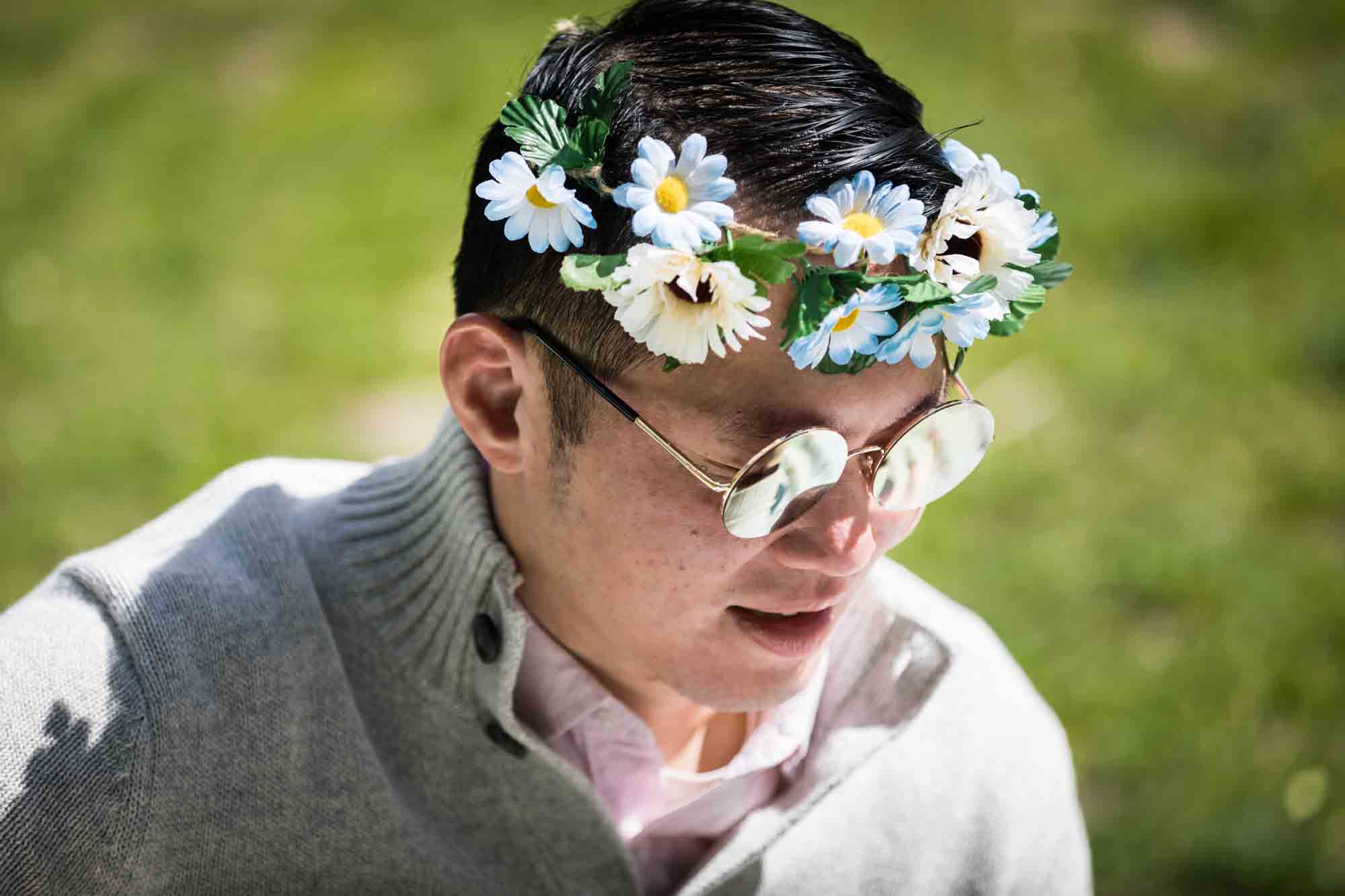 Man wearing Beatle-style sunglasses and a daisy crown
