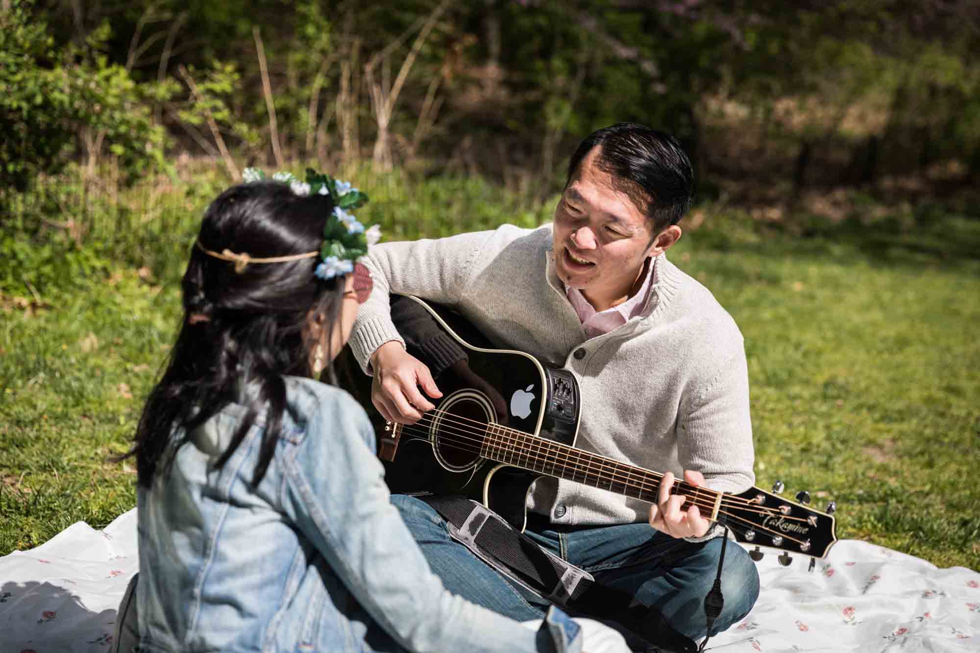Man playing guitar for woman in park