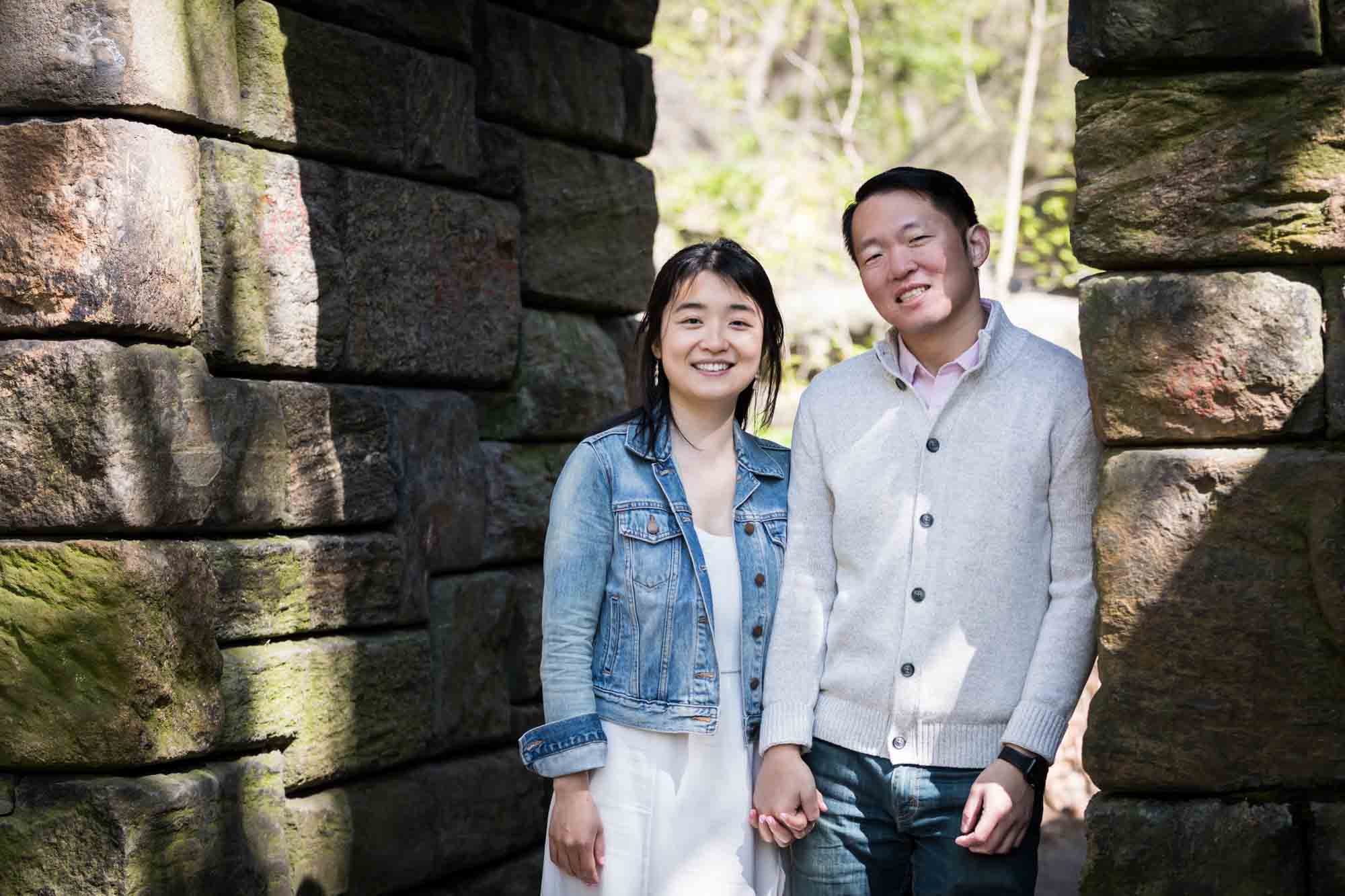 Couple holding hands under Stone Arch in Central Park