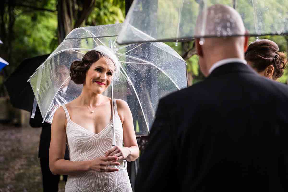 Central Park Wisteria Pergola wedding photos of bride looking at groom while holding umbrella