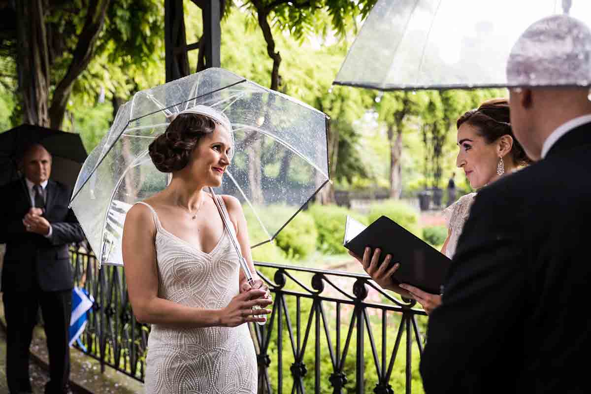 Central Park Wisteria Pergola wedding photos of bride listening to officiant while holding umbrella