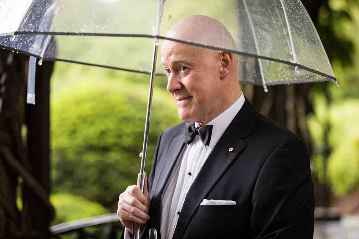 Central Park Wisteria Pergola wedding photos of groom wearing tuxedo and holding clear umbrella