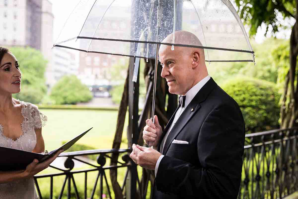 Central Park Wisteria Pergola wedding photos of groom holding ring and clear umbrella