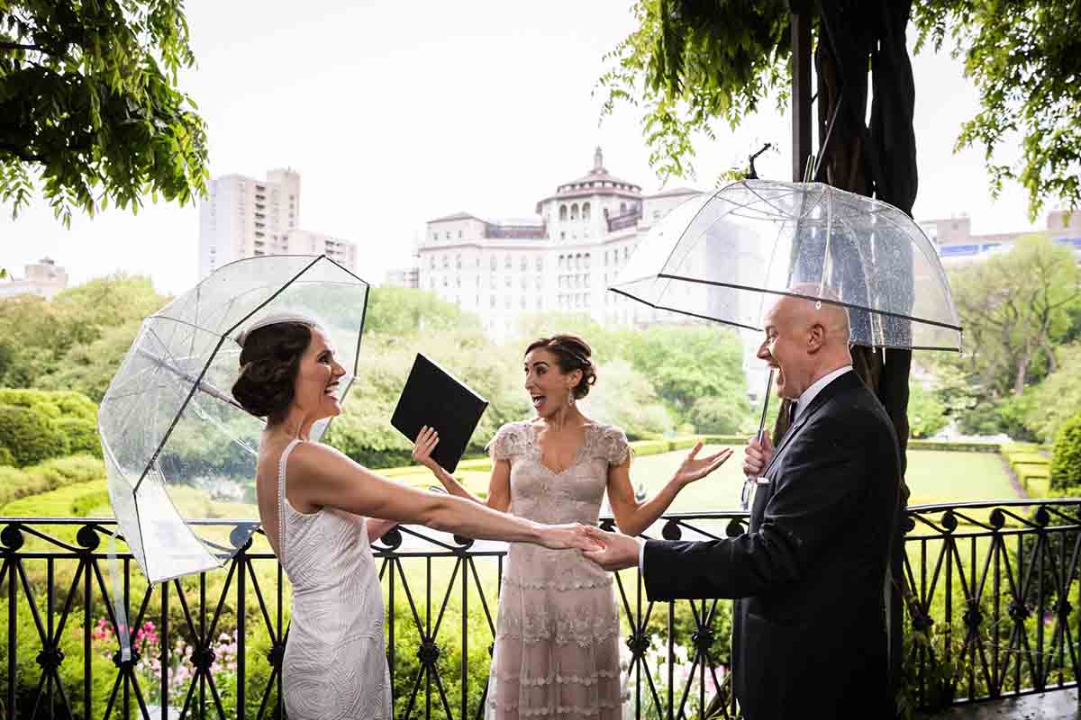 Central Park Wisteria Pergola wedding photos of bride and groom holding hands and clear umbrellas