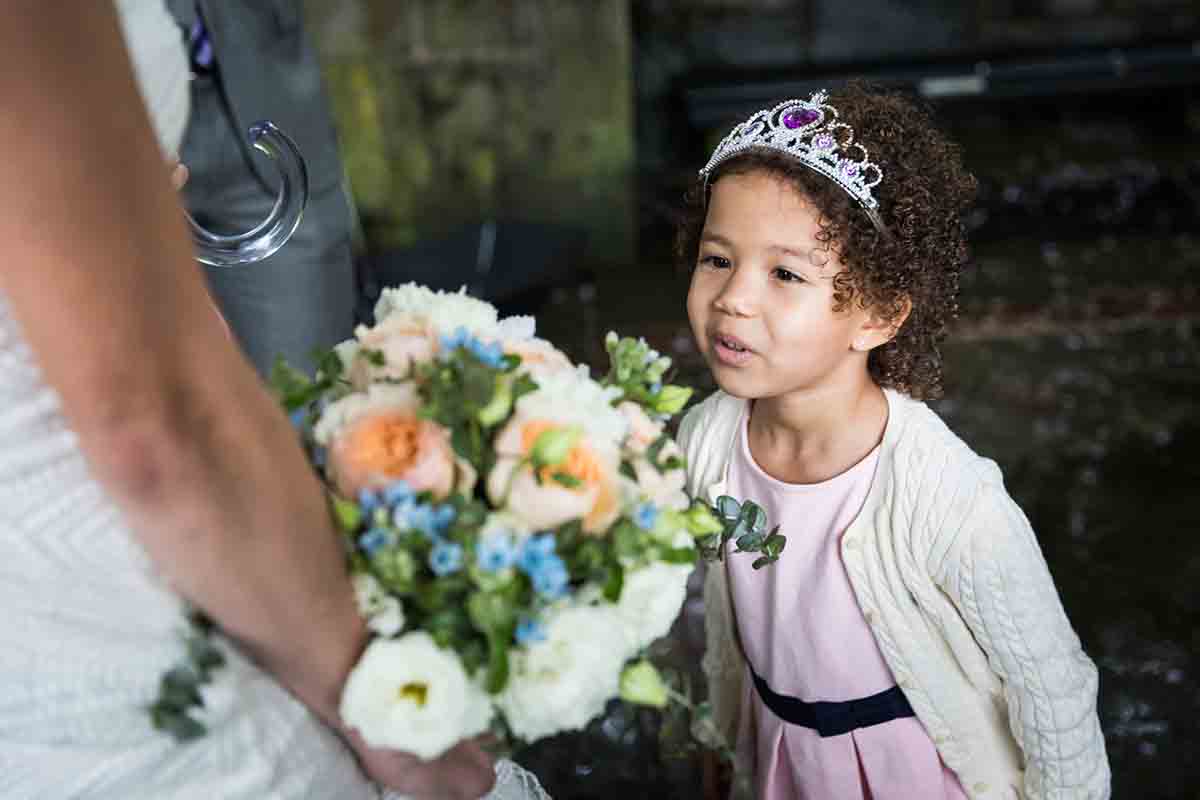 Central Park Wisteria Pergola wedding photos of little girl wearing tiara and looking at bride's bouquet of flowers