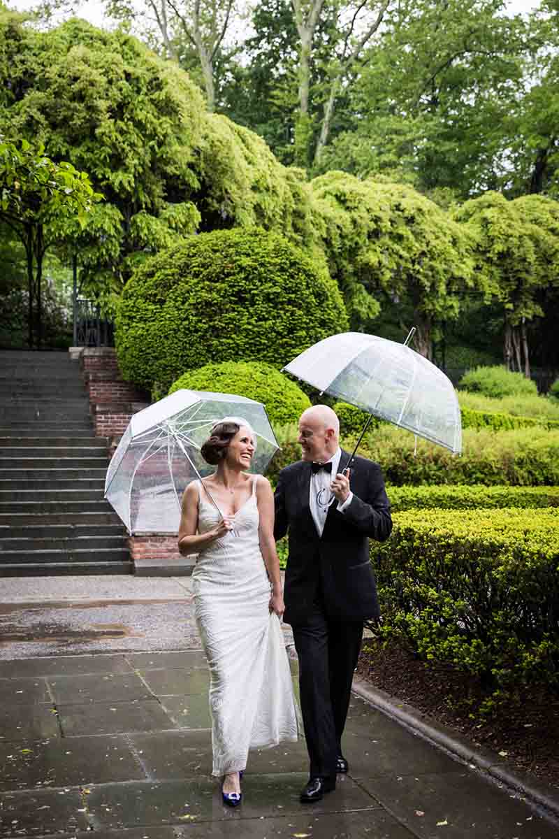 Central Park Wisteria Pergola wedding photos of bride and groom walking in garden holding umbrellas