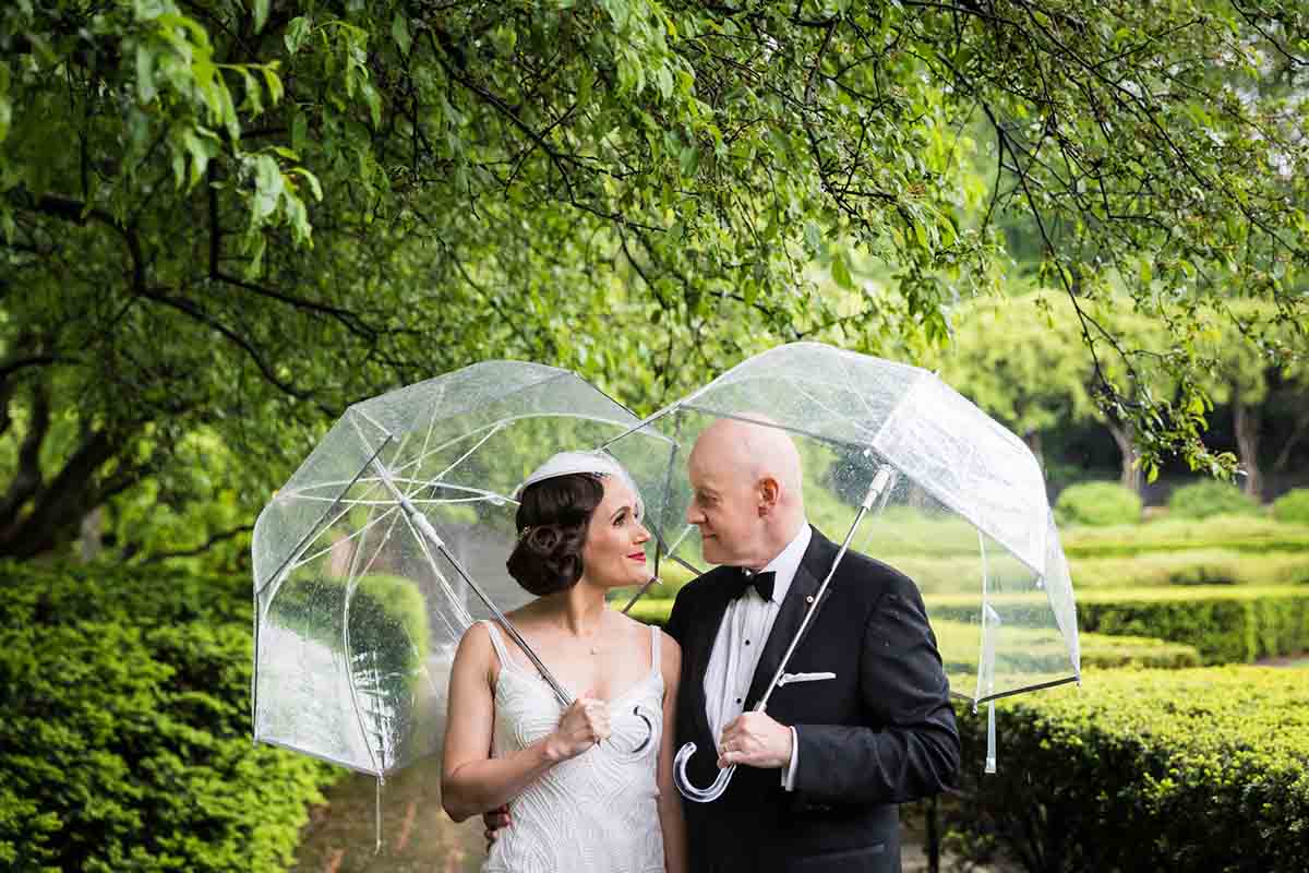 Central Park Wisteria Pergola wedding photos of bride and groom holding clear umbrellas
