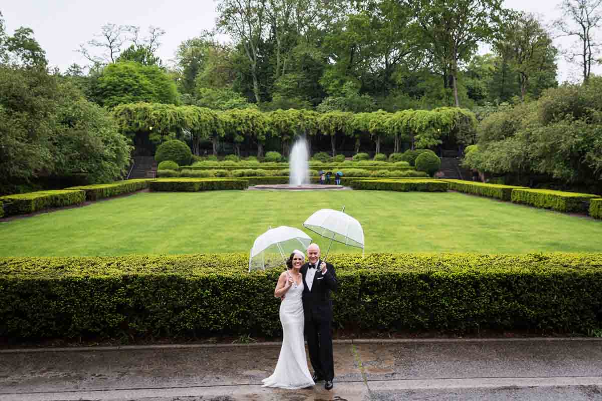 Central Park Wisteria Pergola wedding photos of bride and groom in the Conservatory Garden holding clear umbrellas