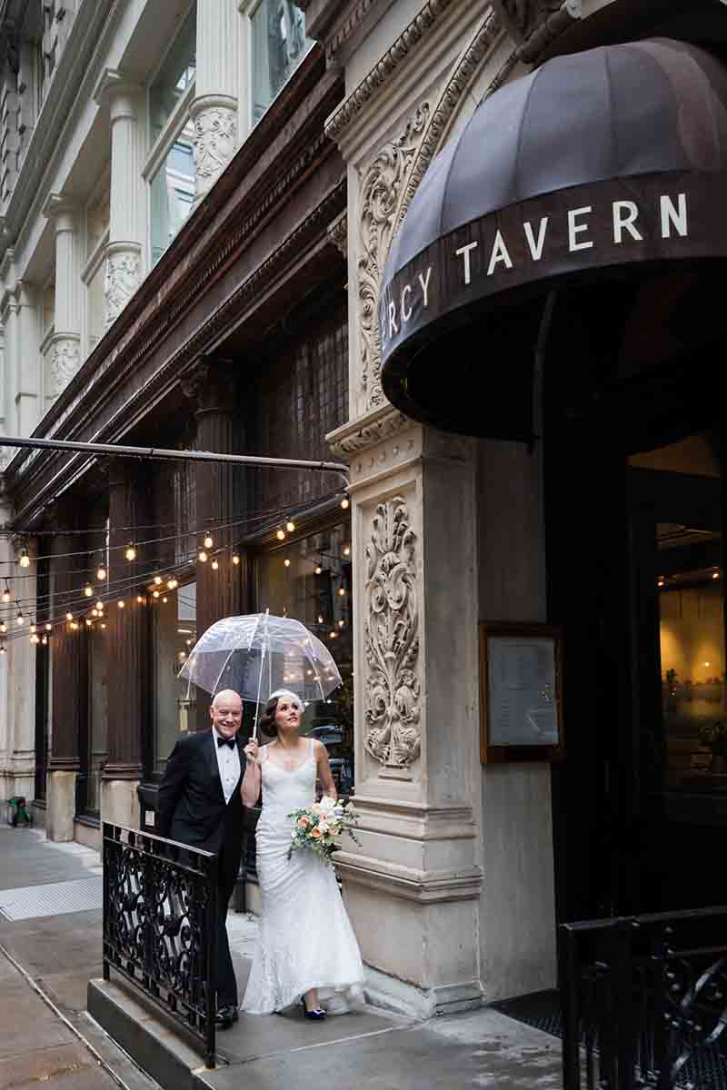 Bride and groom holding umbrellas and walking into Gramercy Tavern