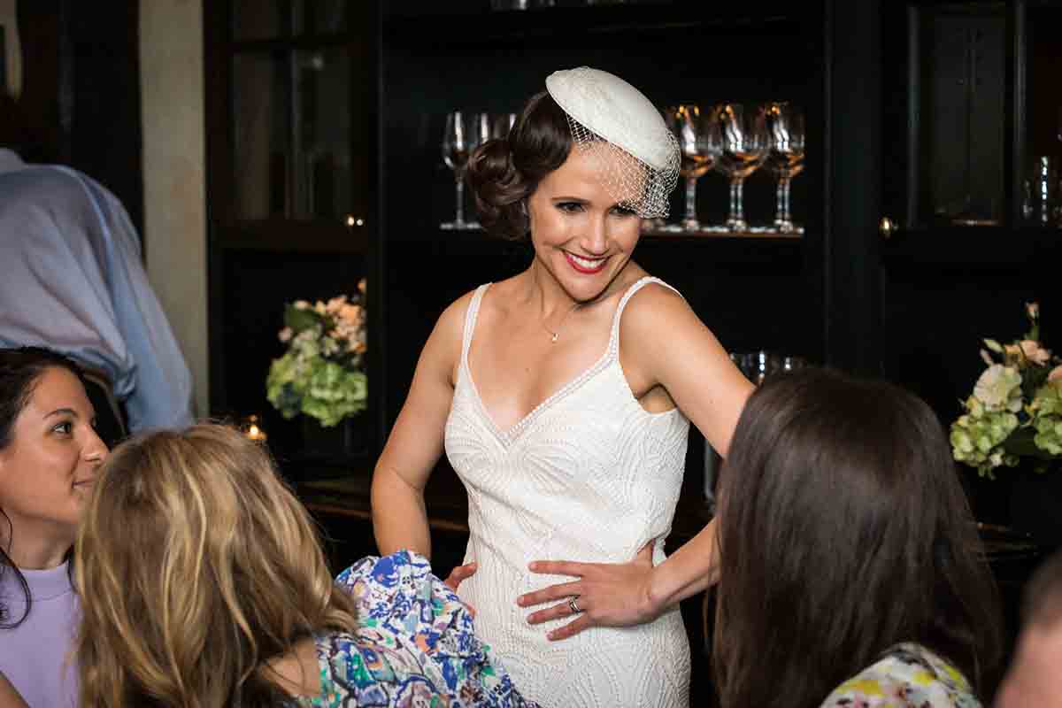 Gramercy Tavern wedding reception photos of bride wearing white hat with veil and hands on hips talking to guests