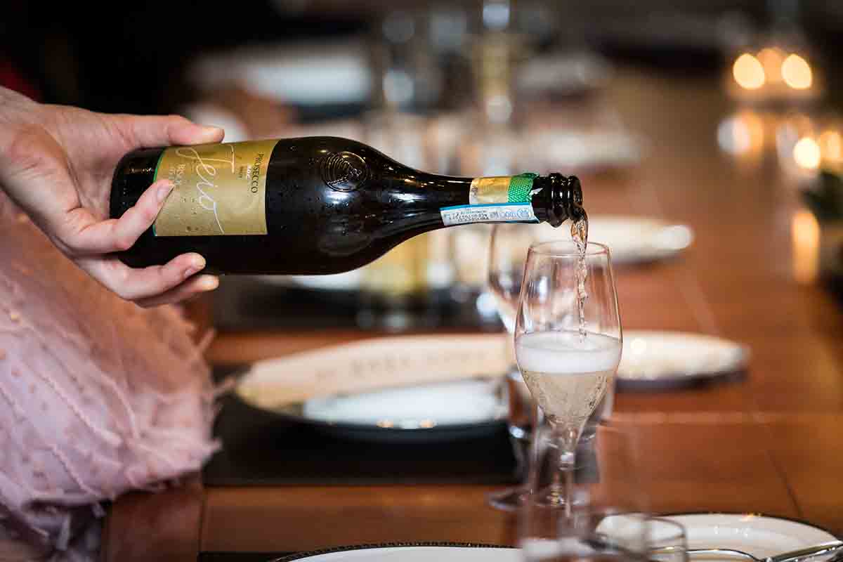 Waiter's hand pouring champagne into a glass