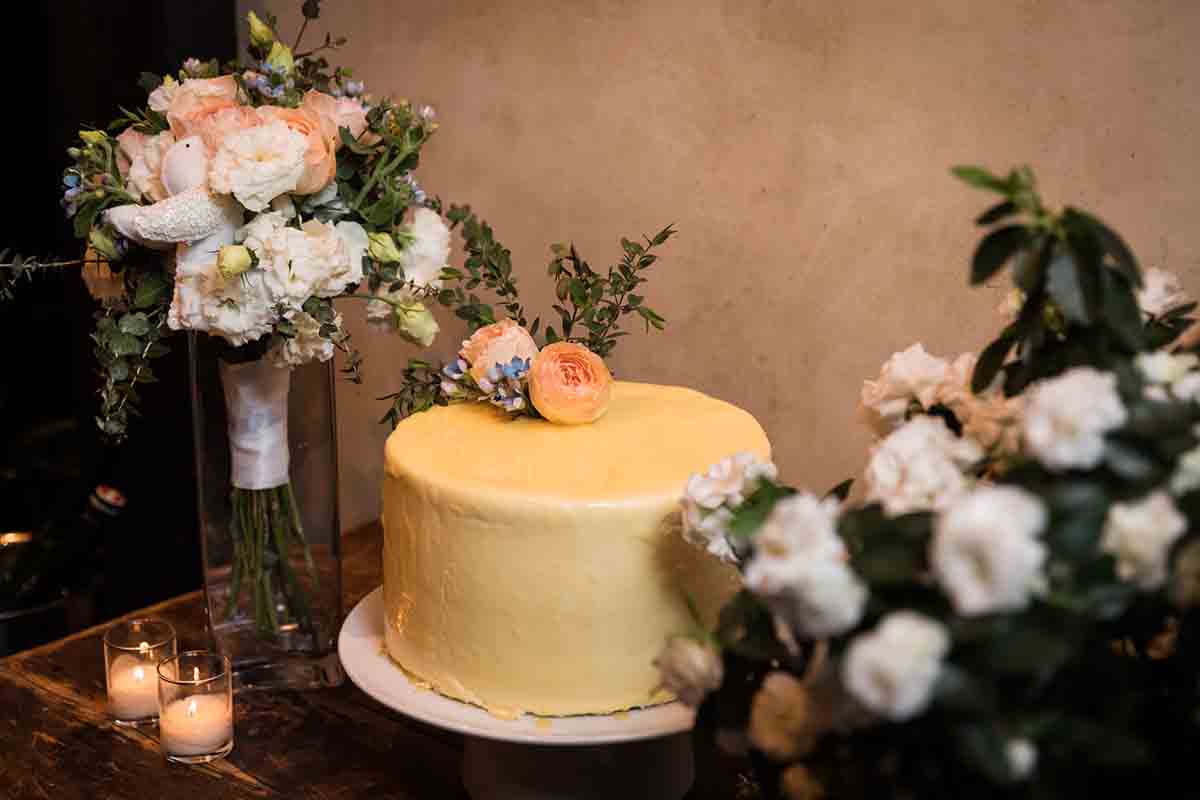 Yellow wedding cake and bouquets of flowers on a table
