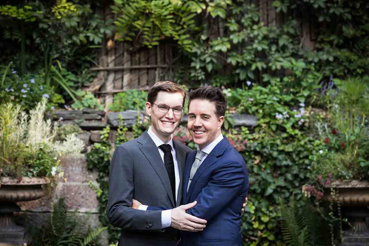 Merchant’s House Museum NYC wedding photos of two grooms hugging in front of vine-covered wall