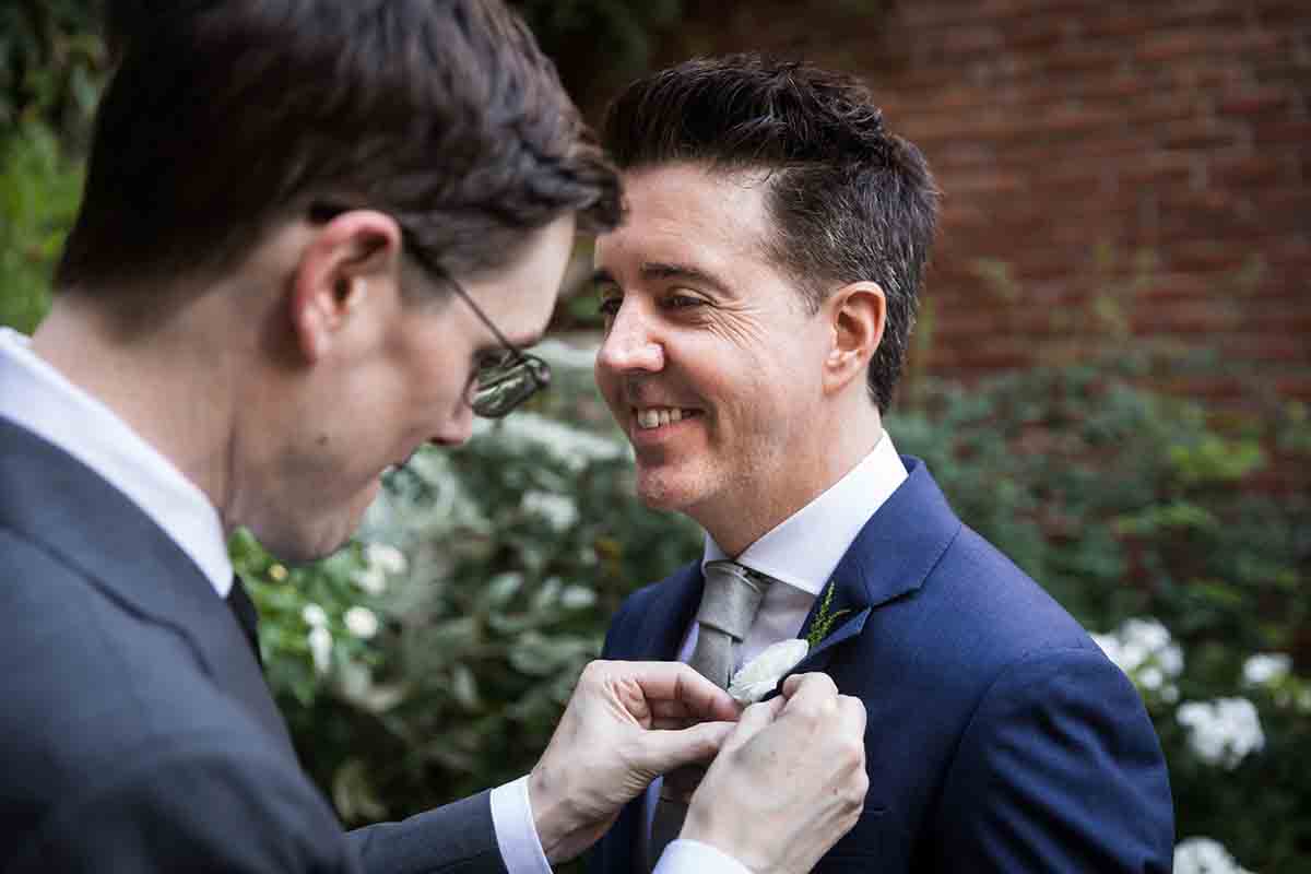 Merchant’s House Museum NYC wedding photos of a man pinning a boutonniere on another man