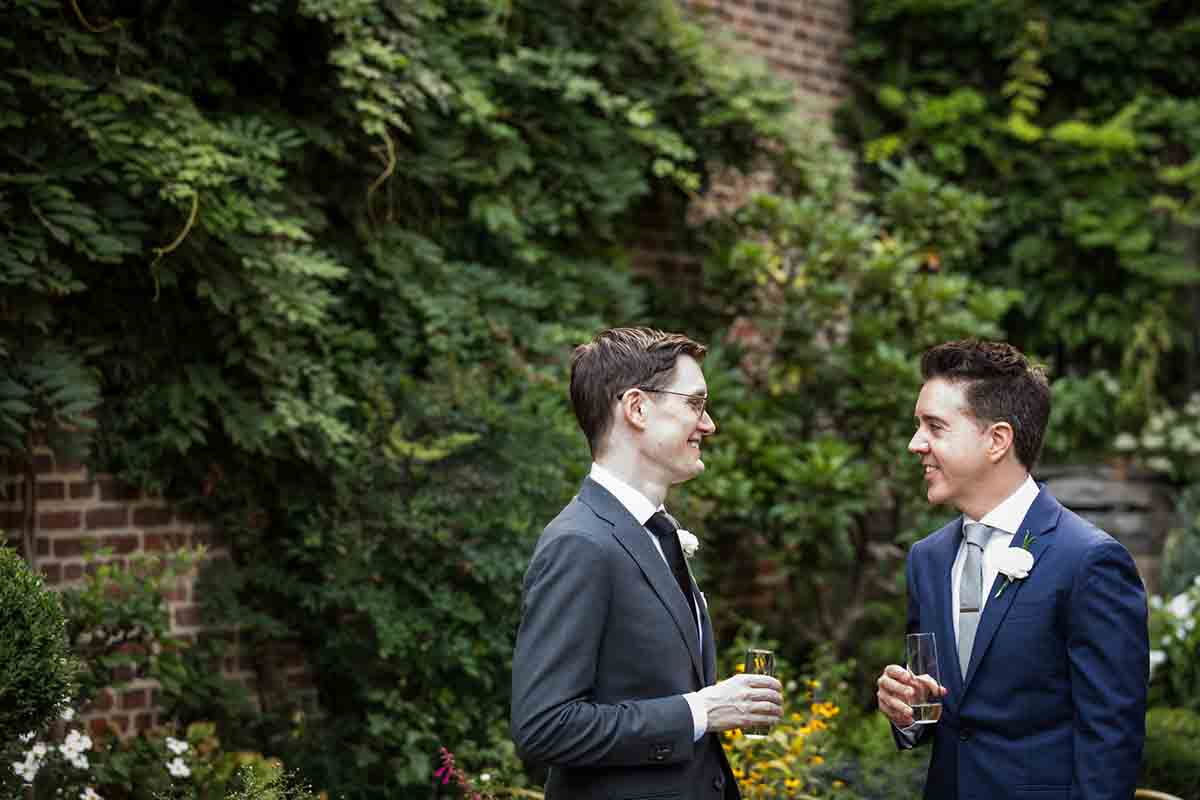 Merchant’s House Museum NYC wedding photos of two grooms holding champagne glasses in the garden