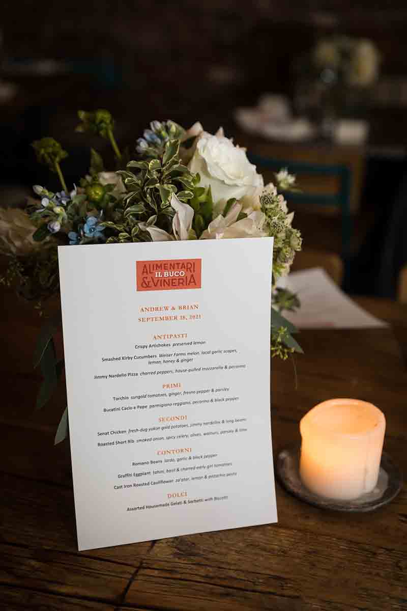 Menu sheet and candle in front of flower bouquet